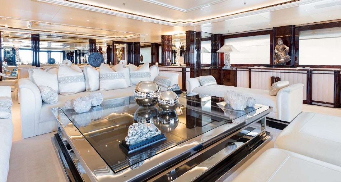a large living room with a large glass coffee table aboard LIONESS V Yacht for Sale