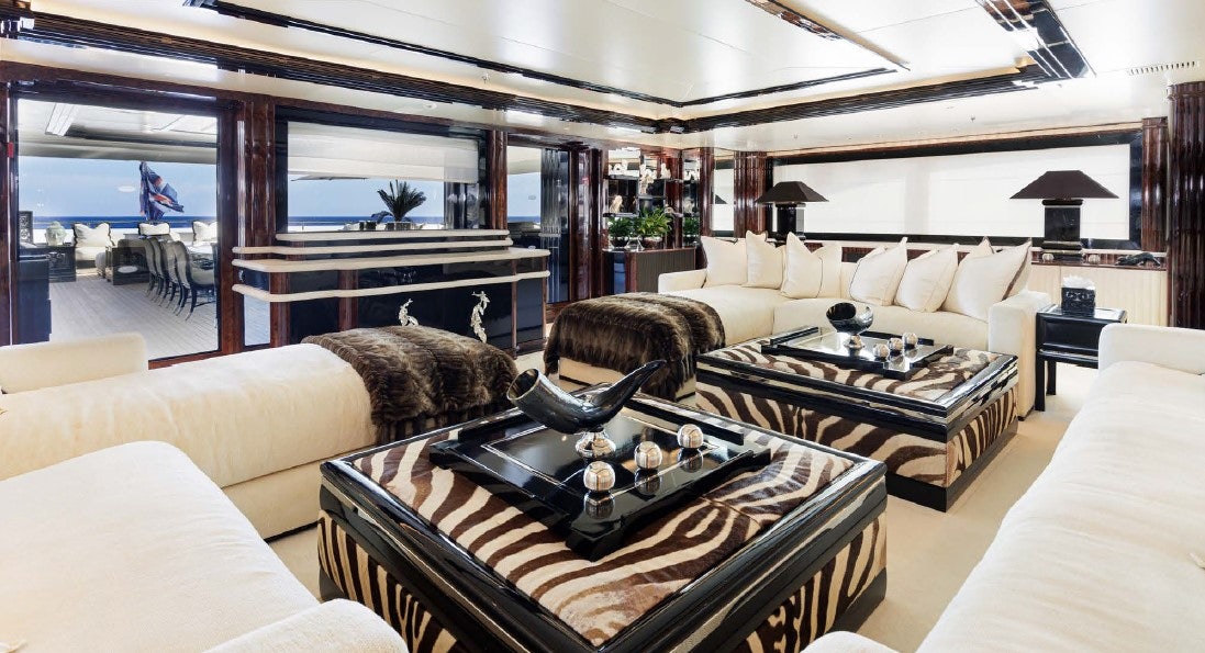 a living room with a large glass coffee table and a large window aboard LIONESS V Yacht for Sale
