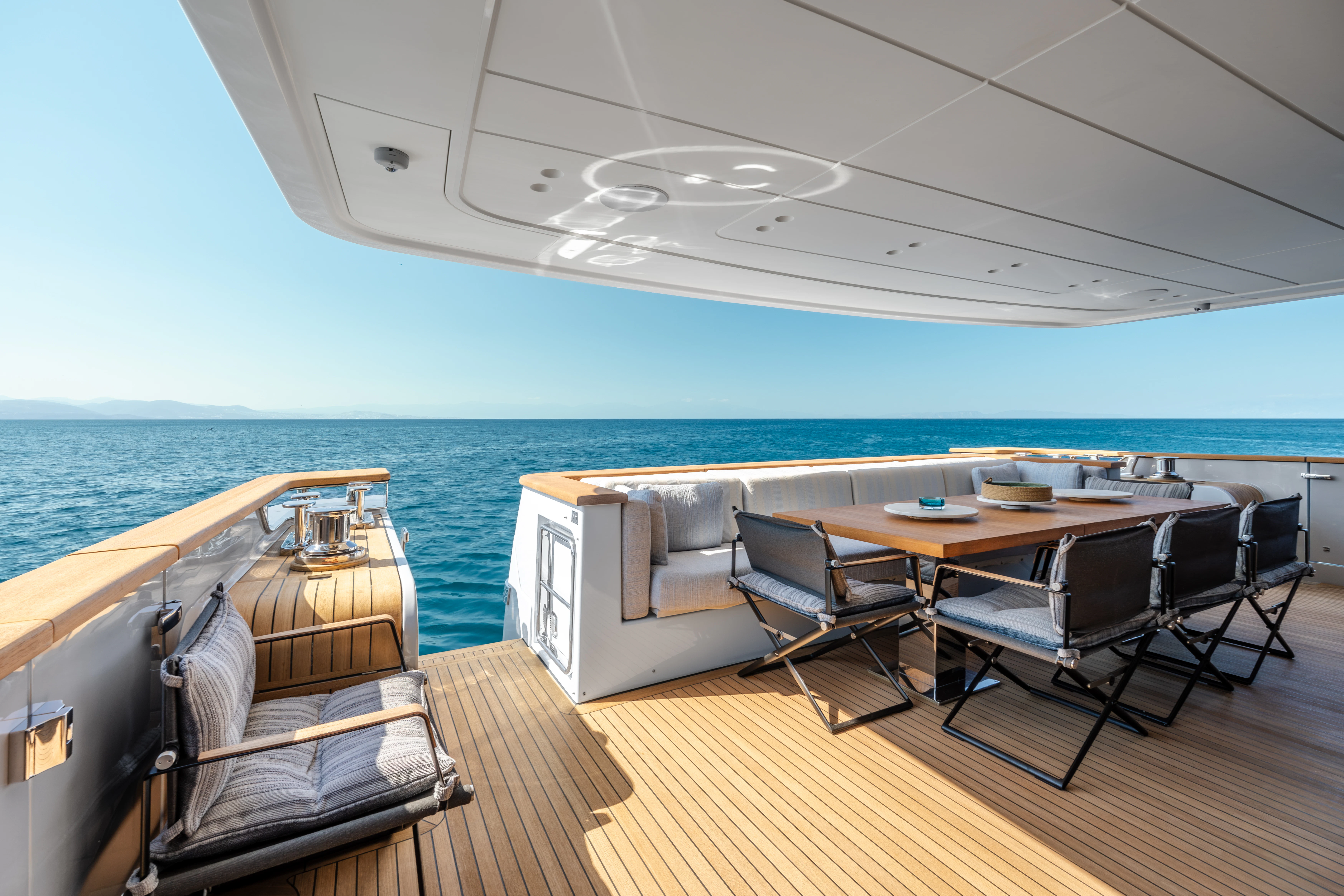 a room with a table and chairs on a deck with a view of the ocean aboard AISHA Yacht for Sale