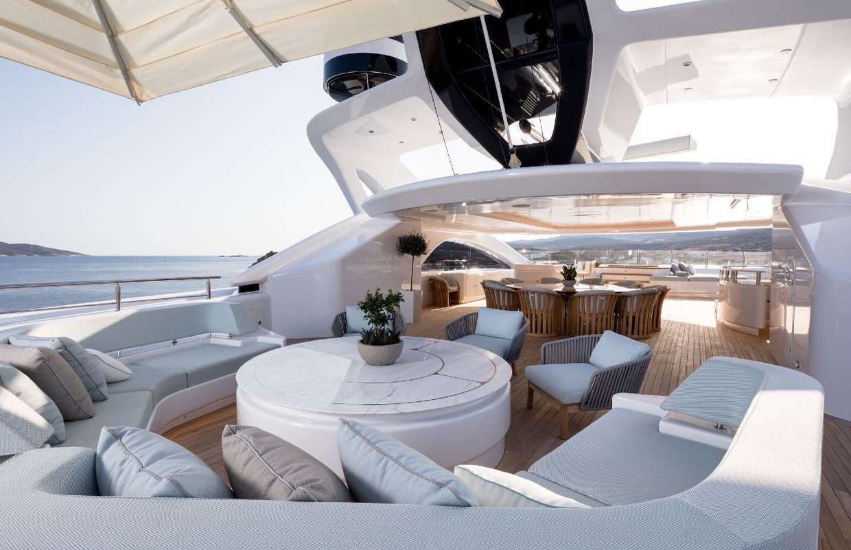 a modern living room with a large white lounge chair and a large white table with a white couch aboard O'PARI Yacht for Charter