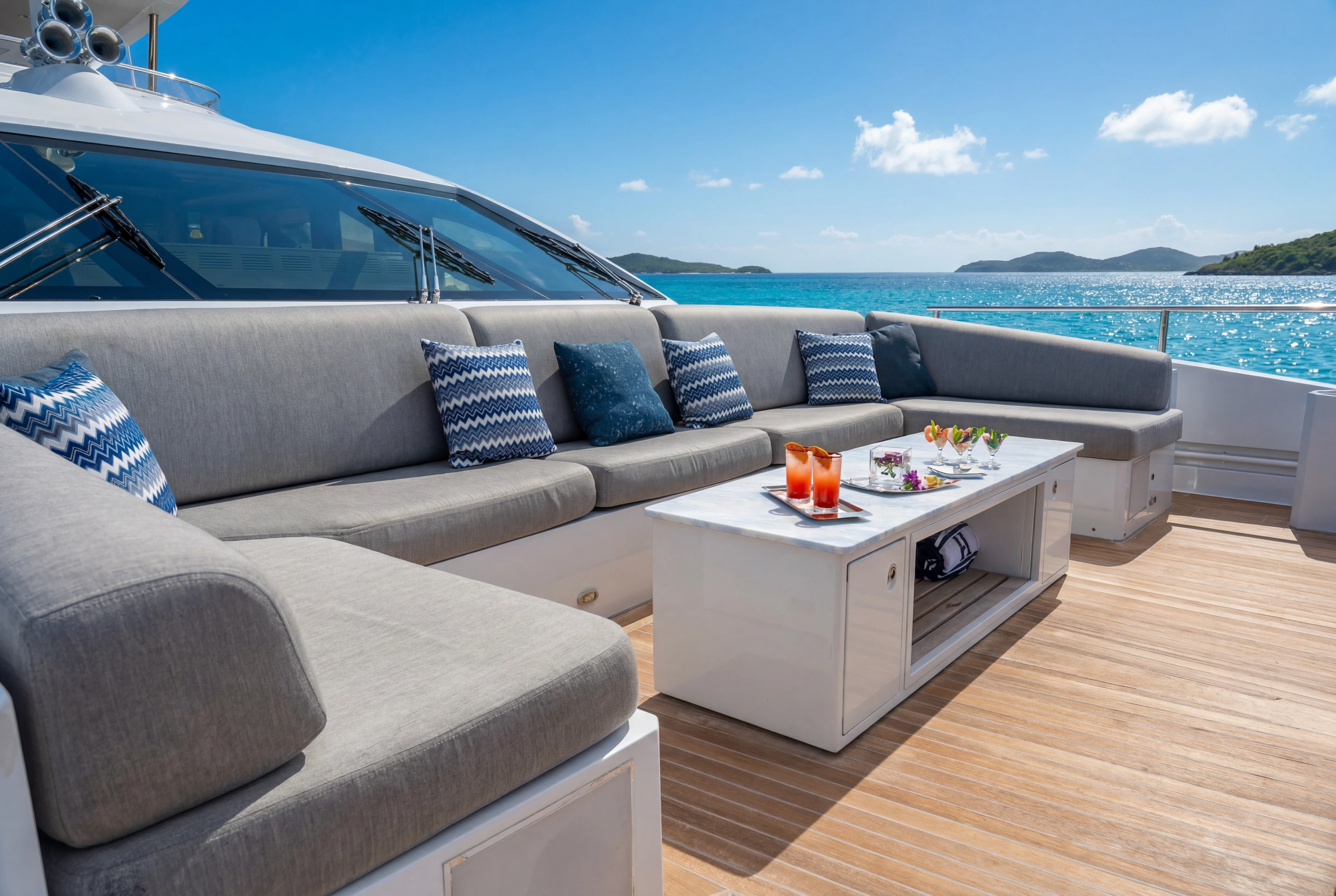 a couch and a table on a deck overlooking a body of water aboard 'H Yacht for Charter
