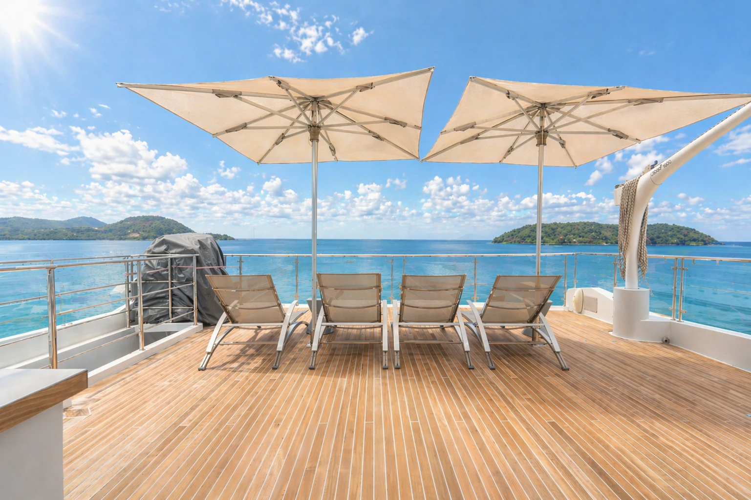 a group of chairs on a deck with an umbrella over the ocean aboard 'H Yacht for Charter