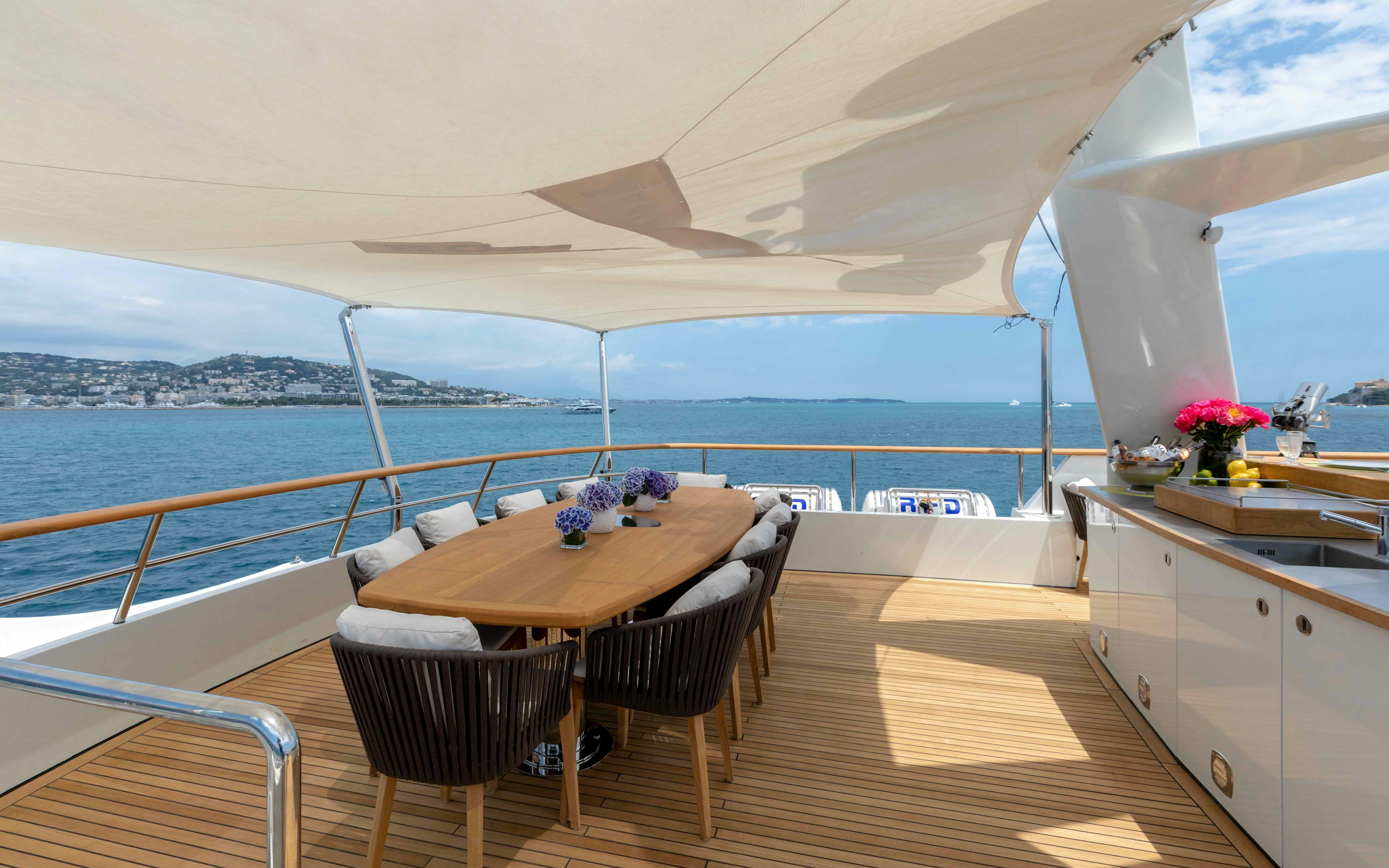 a table and chairs on a deck overlooking a body of water aboard ROBBIE BOBBY Yacht for Sale