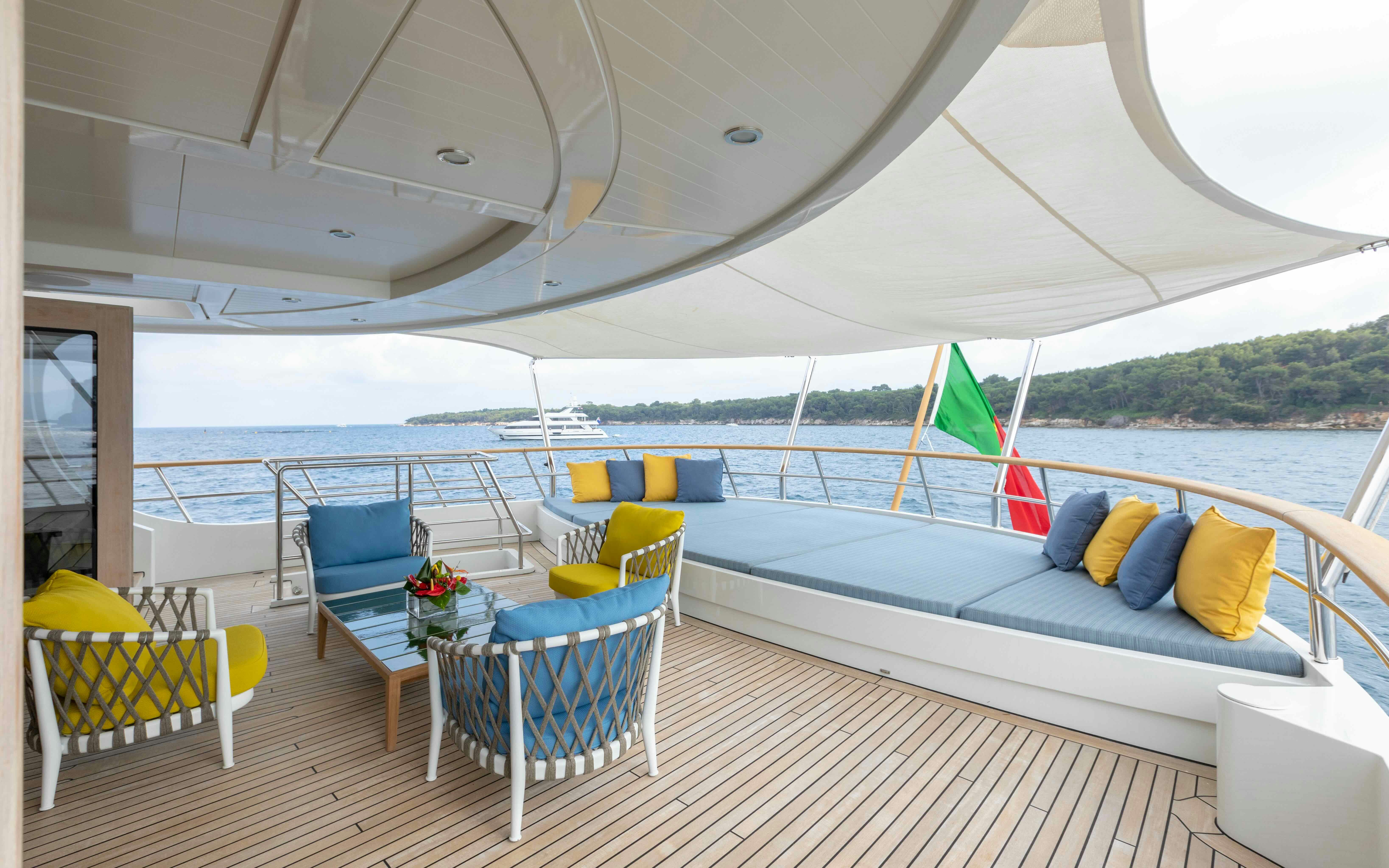 a large white lounge chair on a deck with a large body of water and trees in the background aboard ROBBIE BOBBY Yacht for Sale