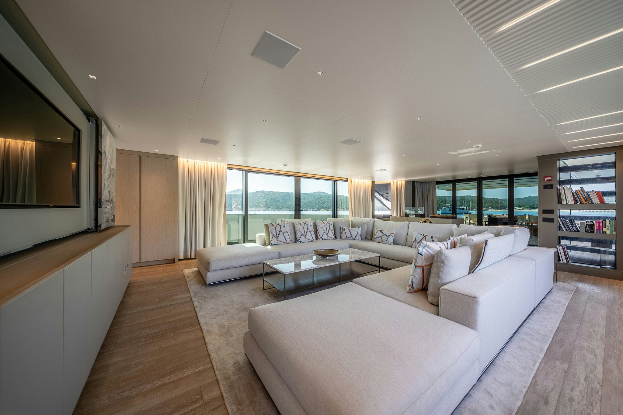 a living room with a large white sofa and a large window aboard BLUE ANGEL Yacht for Sale