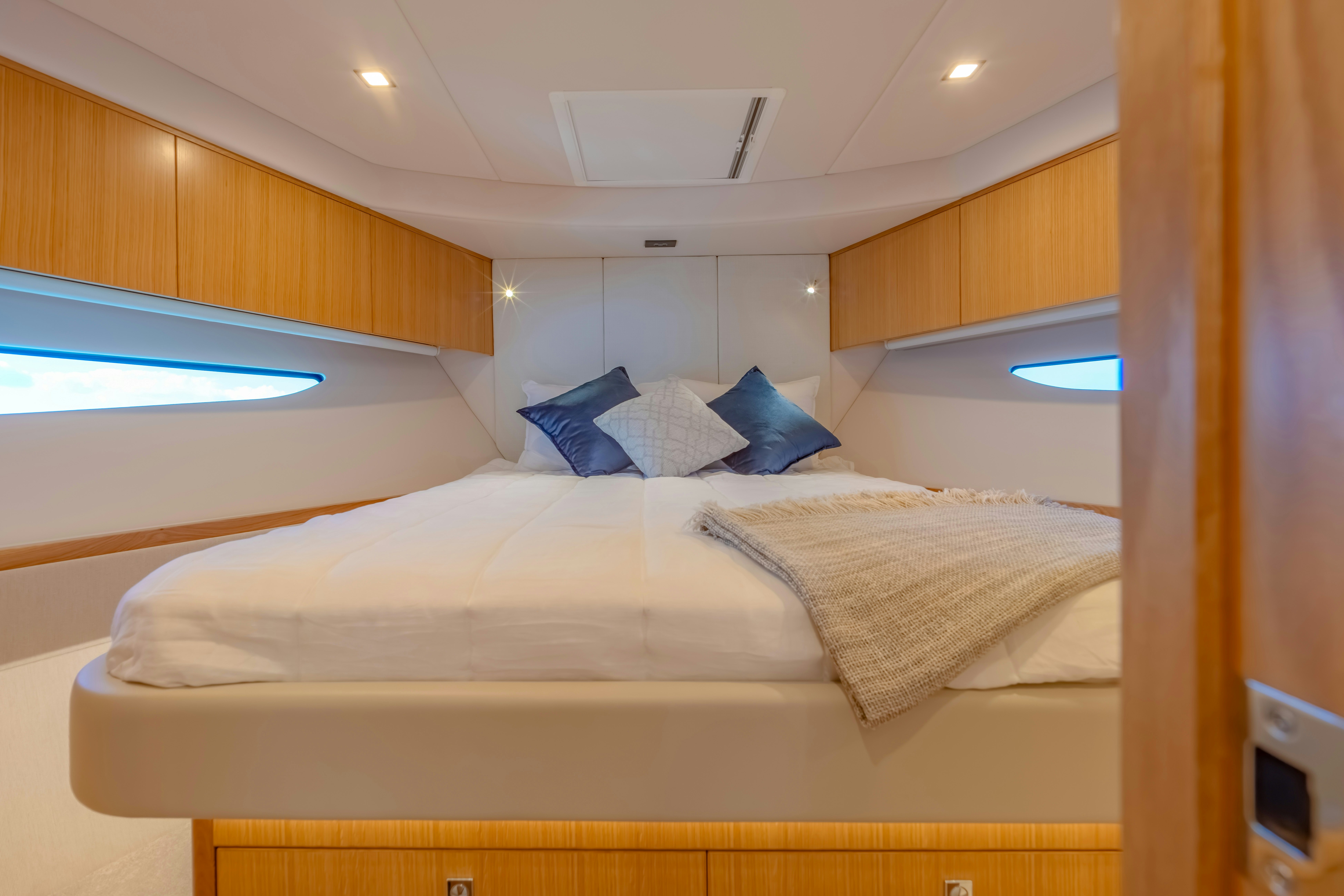 a bed with a white sheet and blue pillows aboard RIVIERA 4600 SPORT YACHT Yacht for Sale