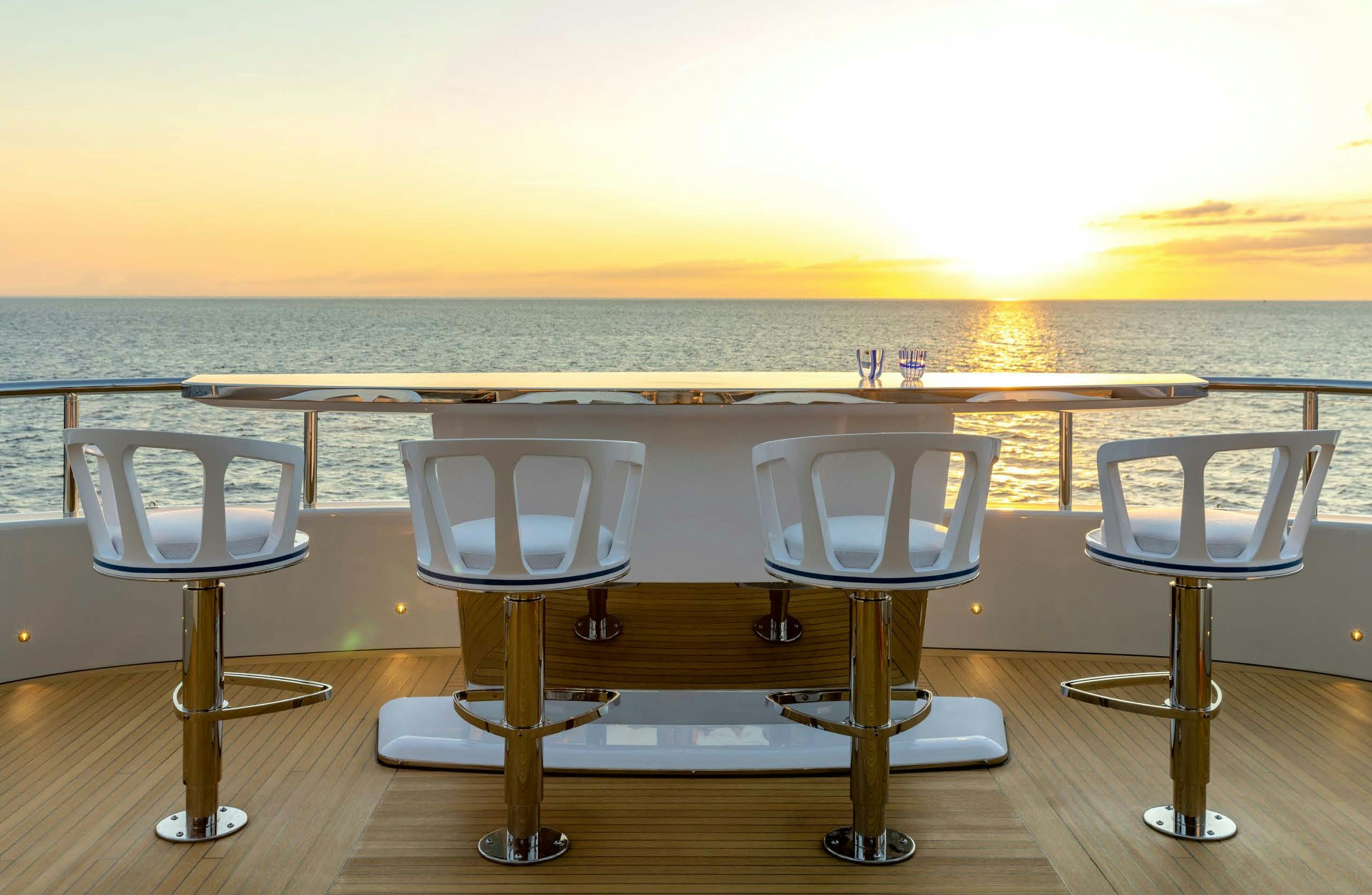 a table and chairs on a deck overlooking a body of water aboard IRYNA II Yacht for Sale