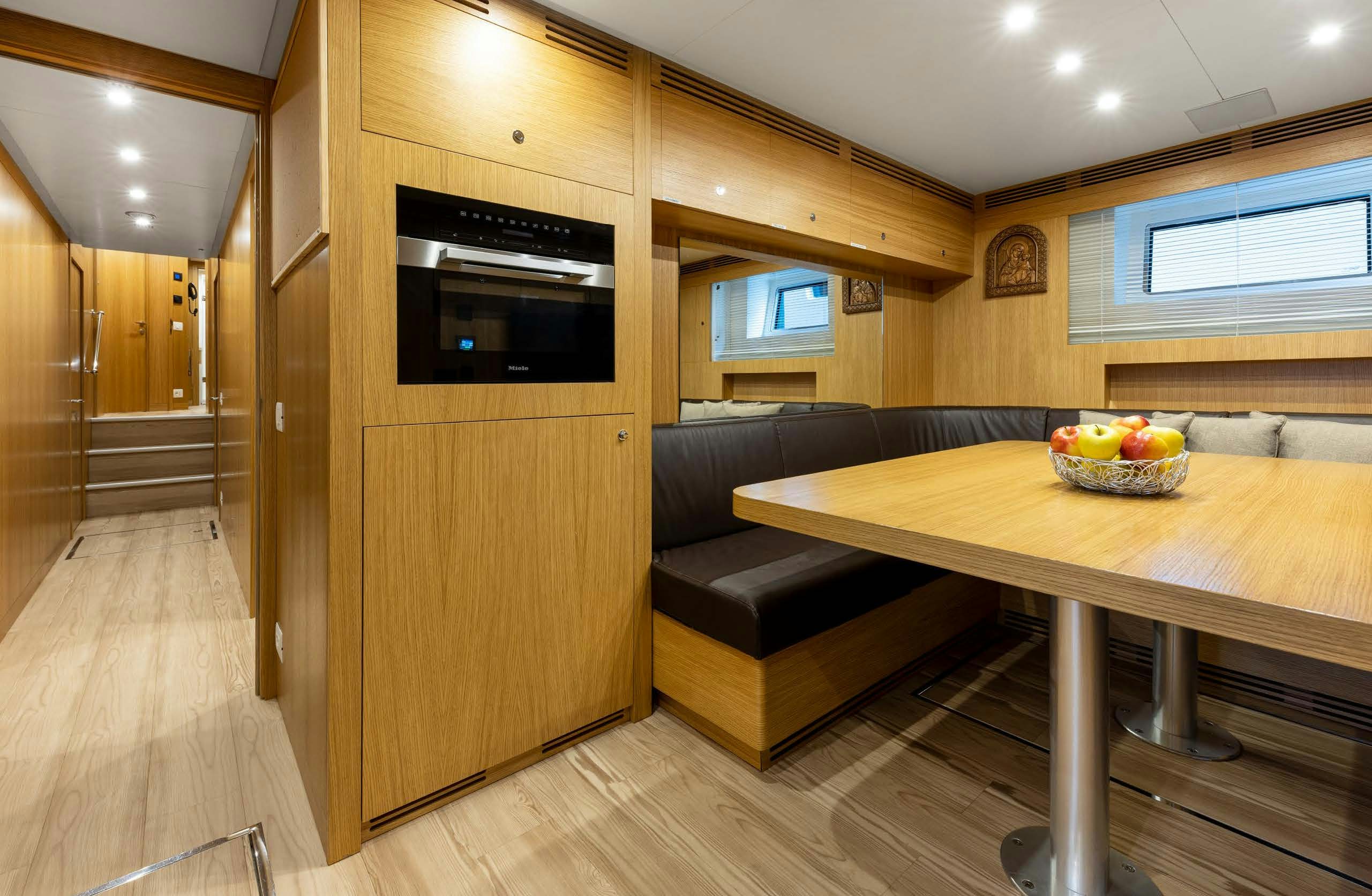 a kitchen with a wood table and couches aboard IRYNA II Yacht for Sale