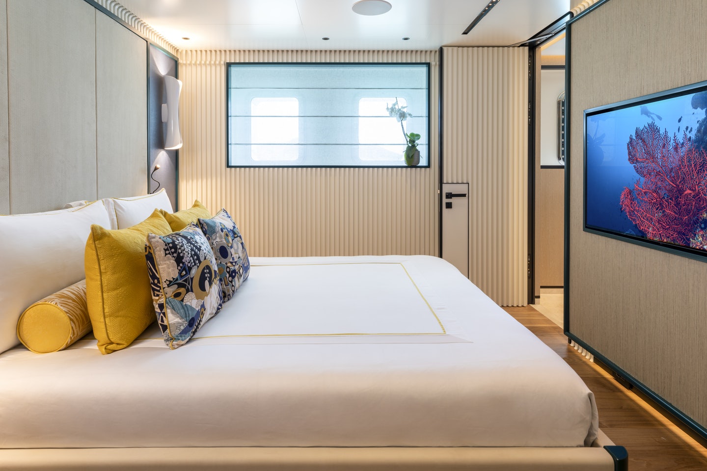 a bed with pillows and a tv on the wall aboard RIO Yacht for Charter
