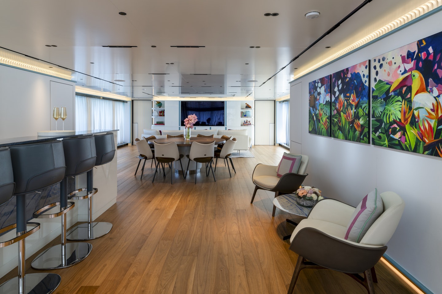 a room with a wood floor and white chairs and a large screen aboard RIO Yacht for Charter