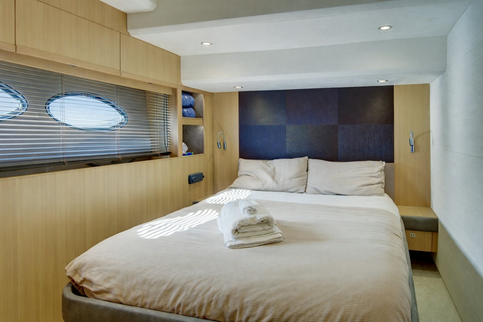 a bed with a white sheet and a blue pillow on it aboard GRAND CRU Yacht for Sale
