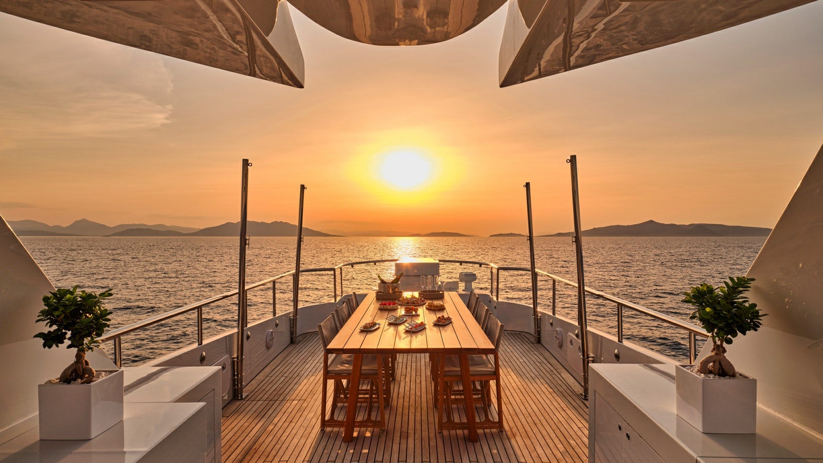 a table and chairs on a balcony overlooking a body of water aboard GELLY Yacht for Charter