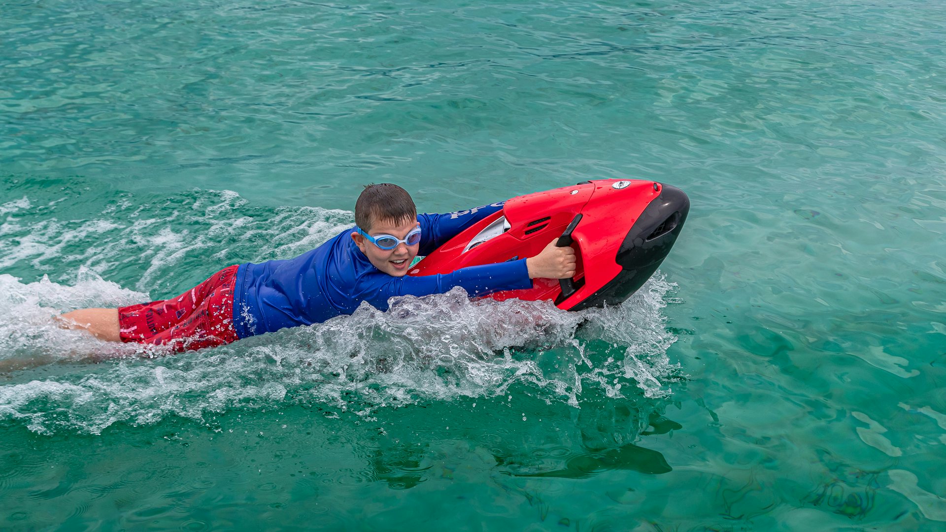 a man lying on a surfboard in the water aboard HIGHLANDER Yacht for Charter