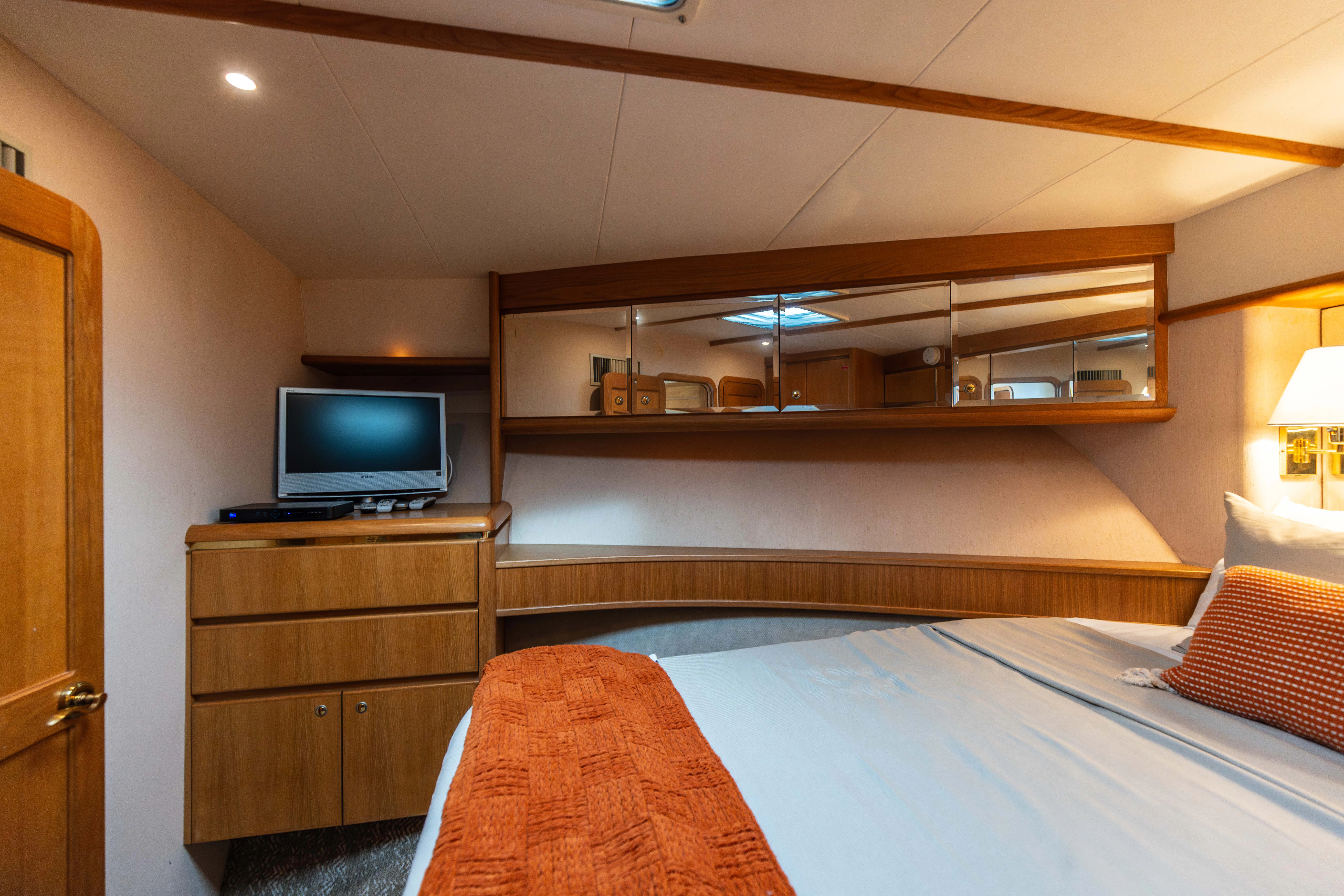 a bedroom with a tv and a bed aboard 3TEN Yacht for Sale