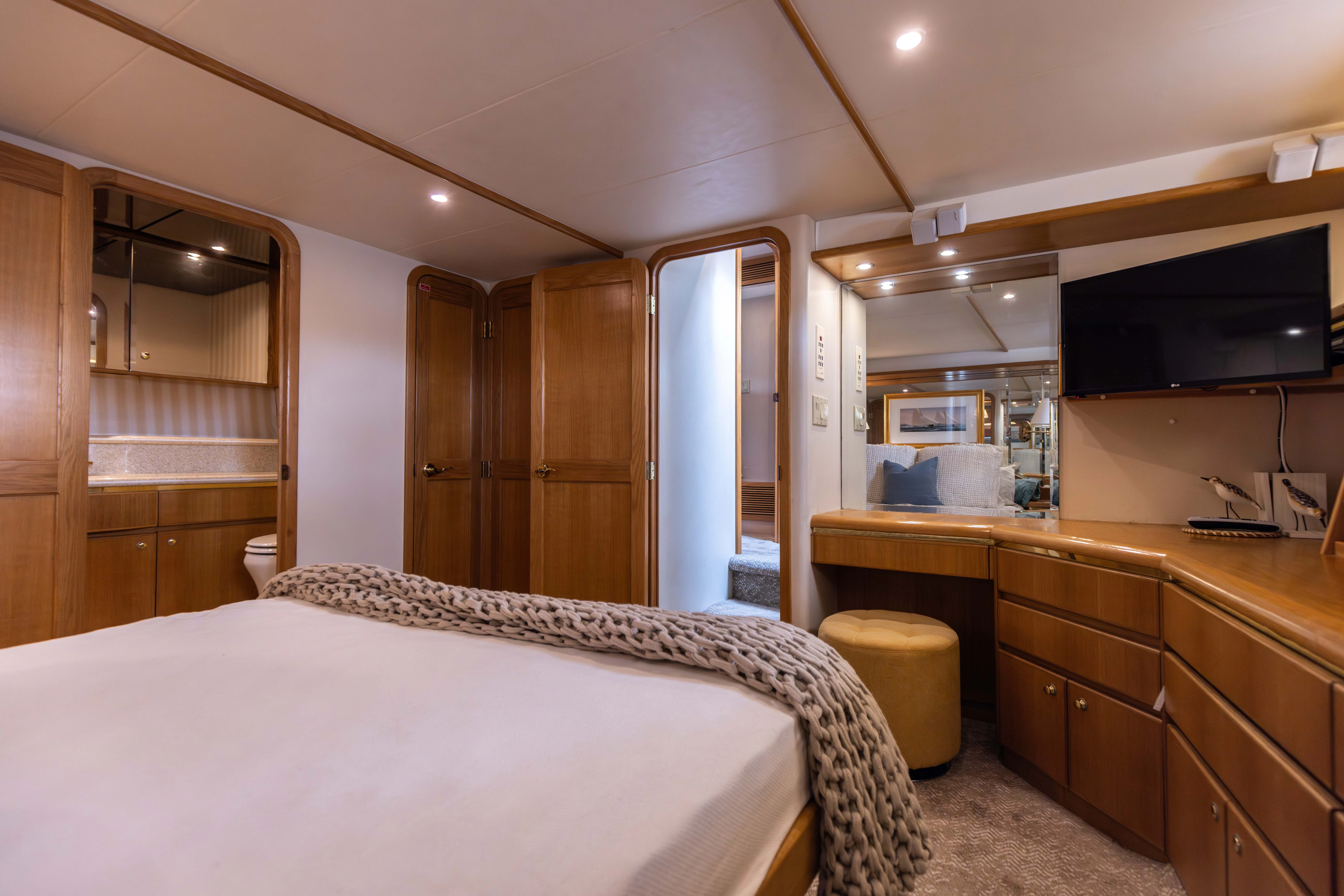 a bedroom with a bed and a tv aboard 3TEN Yacht for Sale