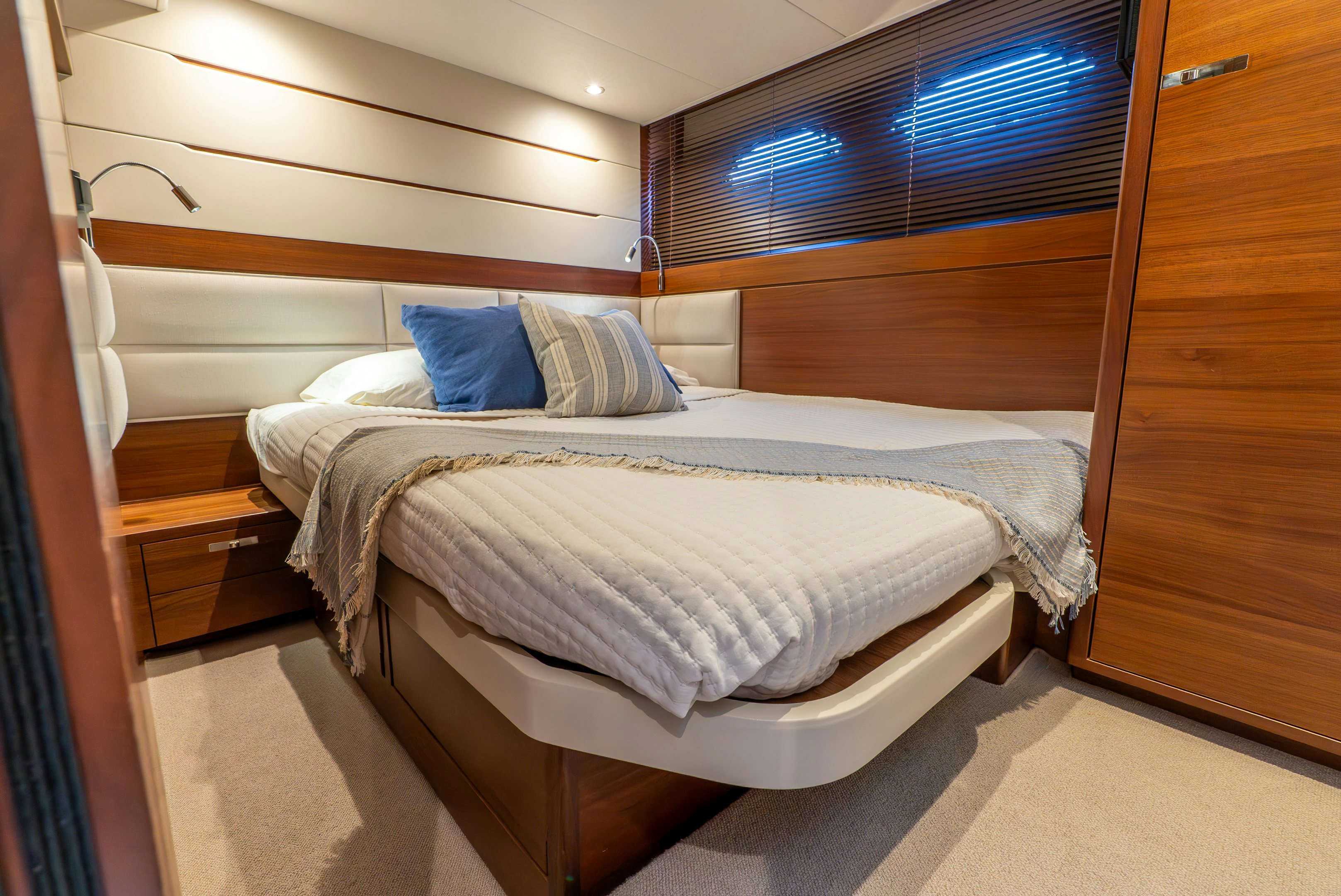 a bed with a white sheet and blue pillows aboard MAMU Yacht for Sale