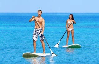 a man and woman on paddle boards in the ocean aboard RELENTLESS Yacht for Charter