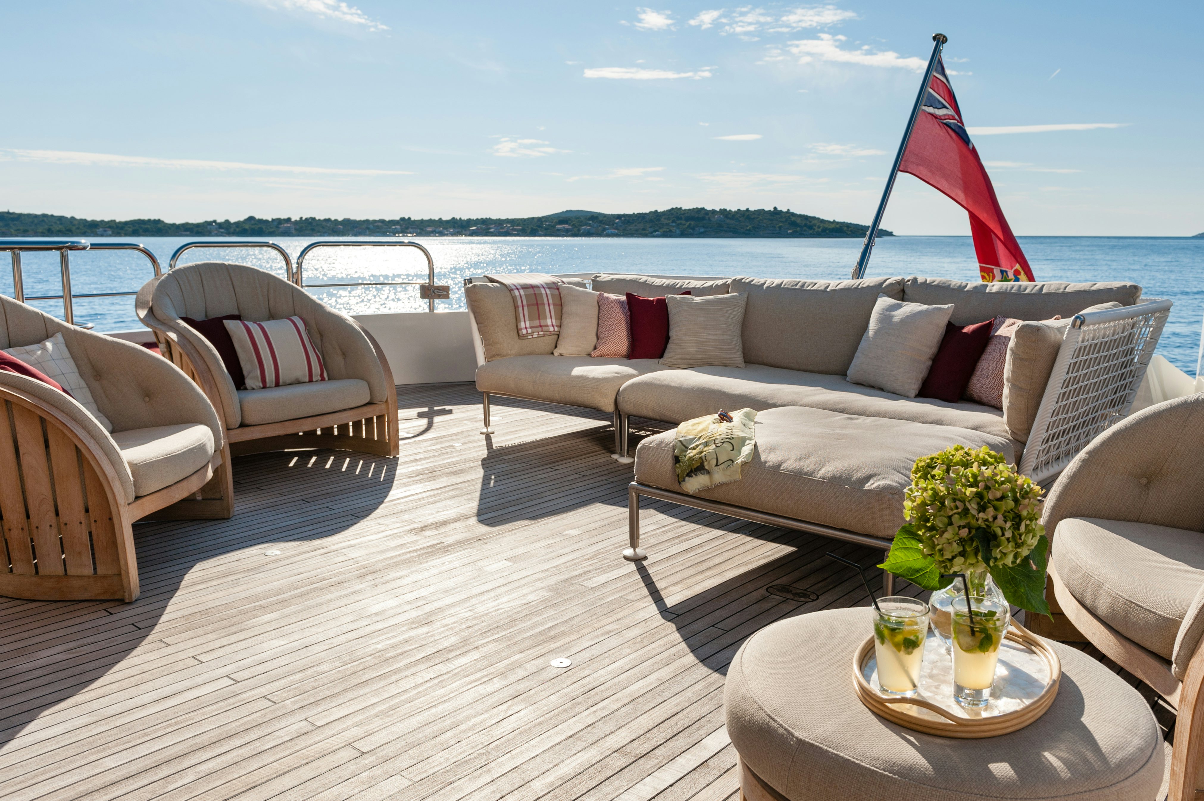 a living room with a large sofa and a table with a red flag aboard METSUYAN IV Yacht for Charter