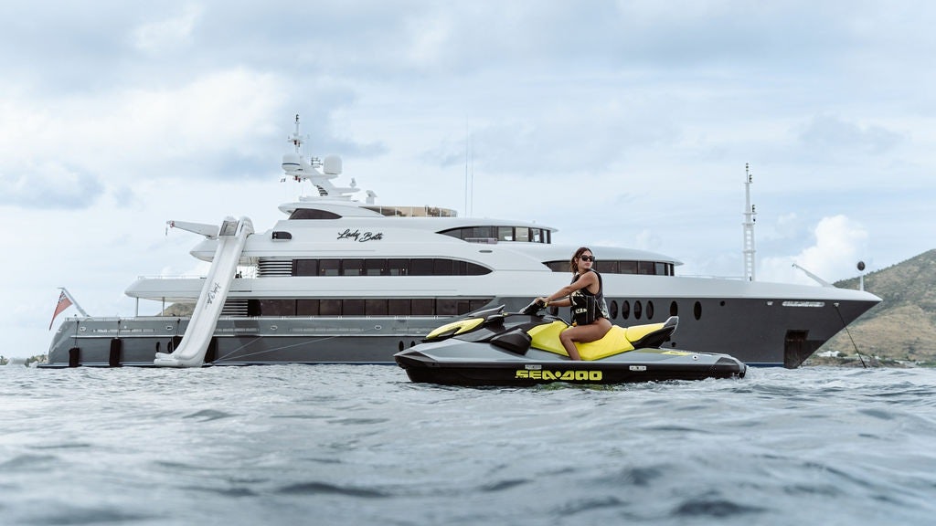 a person on a jet ski in the water next to a large boat aboard LADY BETH Yacht for Charter