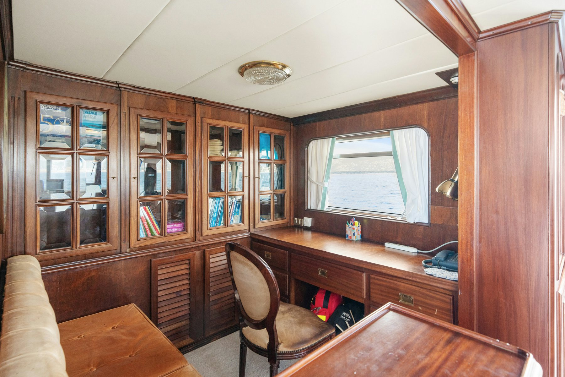 a room with wooden cabinets and a couch and a window aboard AMMIRAGLIO Yacht for Sale