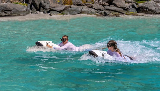 a man and woman riding a surfboard in the ocean aboard SCOTT FREE Yacht for Charter