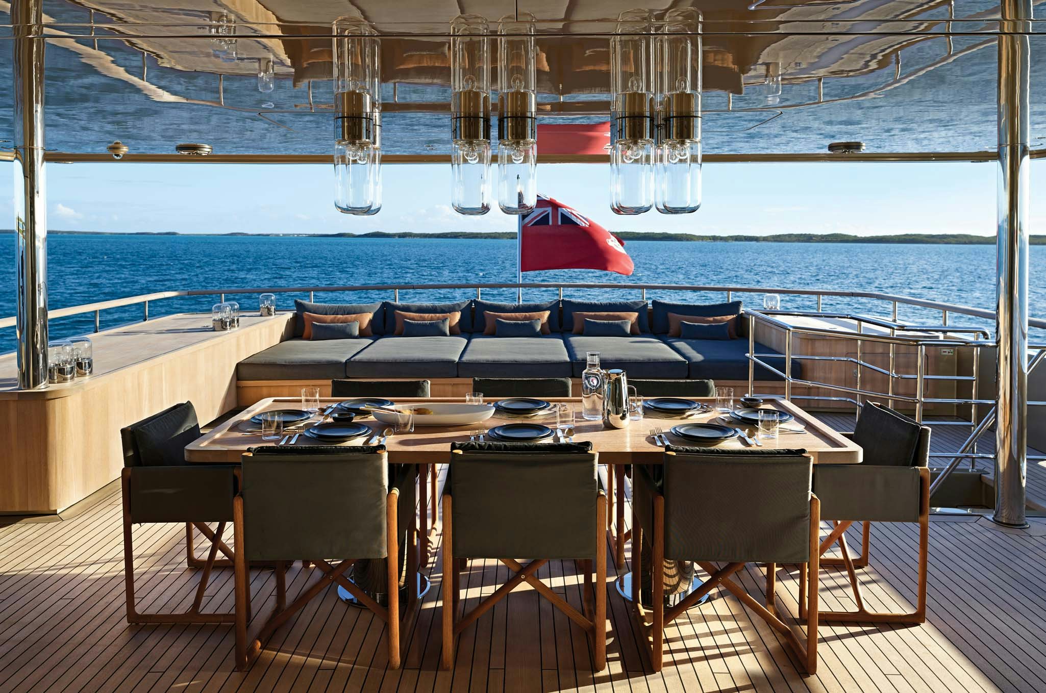 a table with chairs and a red umbrella on a deck aboard RH THREE Yacht for Charter