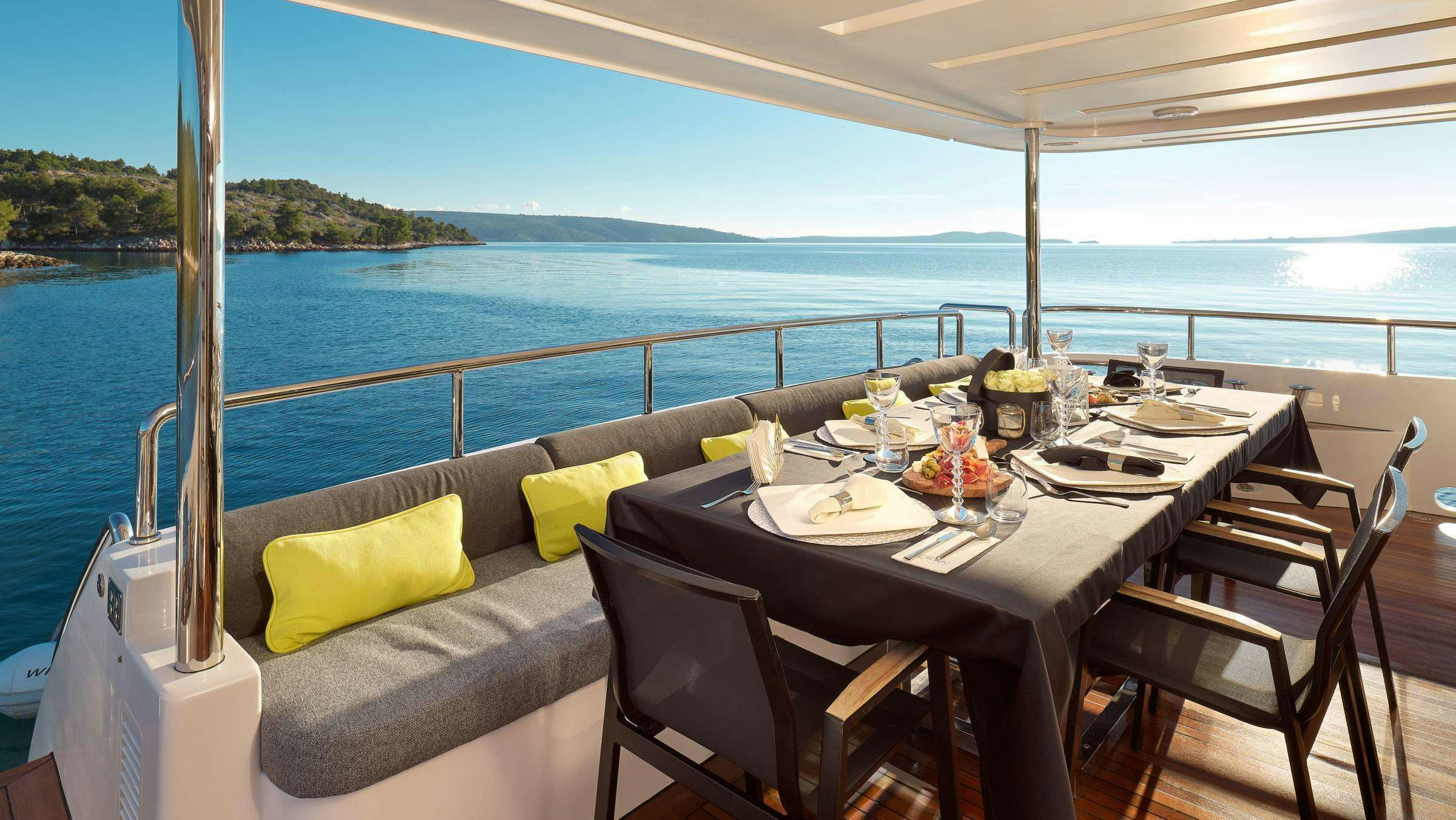 a table with a set of chairs on it next to a large body of water aboard OCEAN DRIVE Yacht for Charter