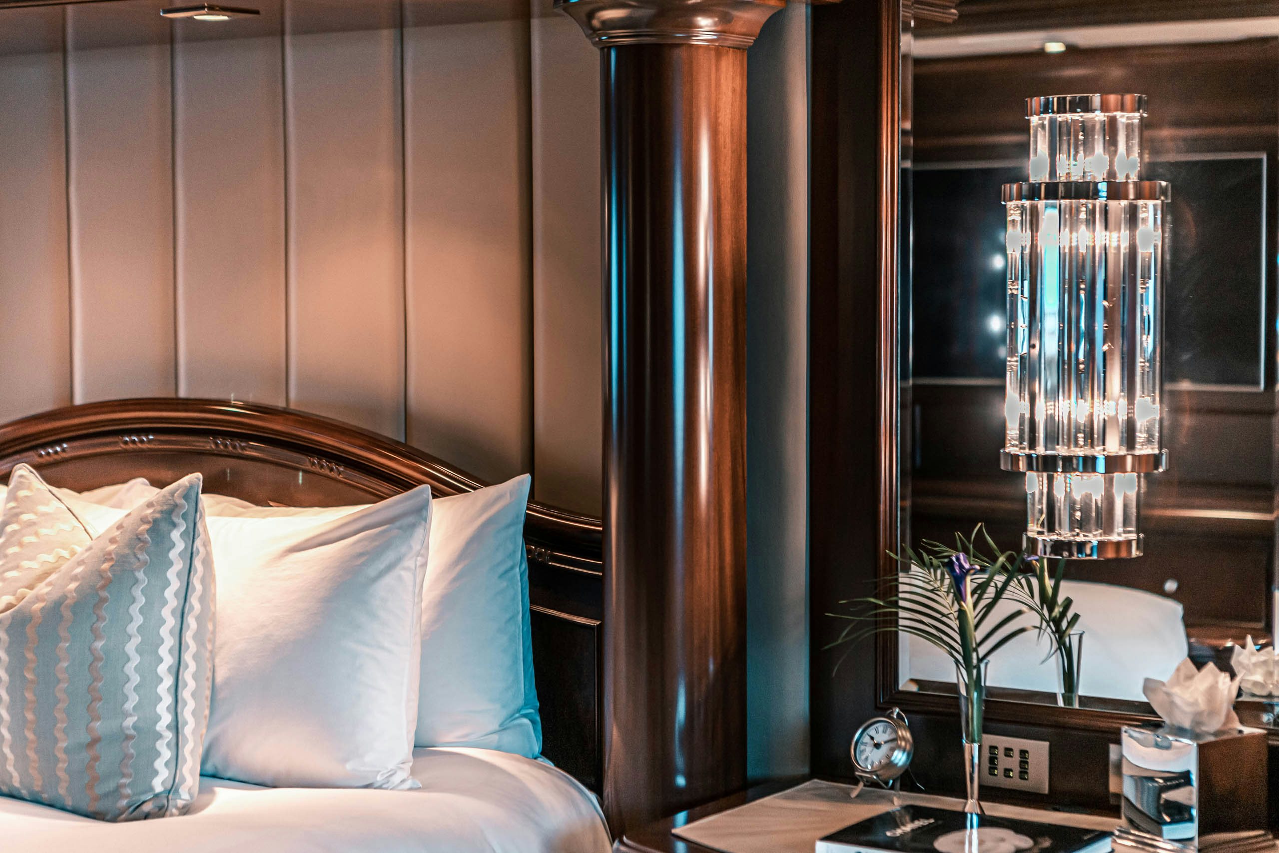 a bed with a lamp and a vase with flowers on it aboard MIRABELLA Yacht for Charter