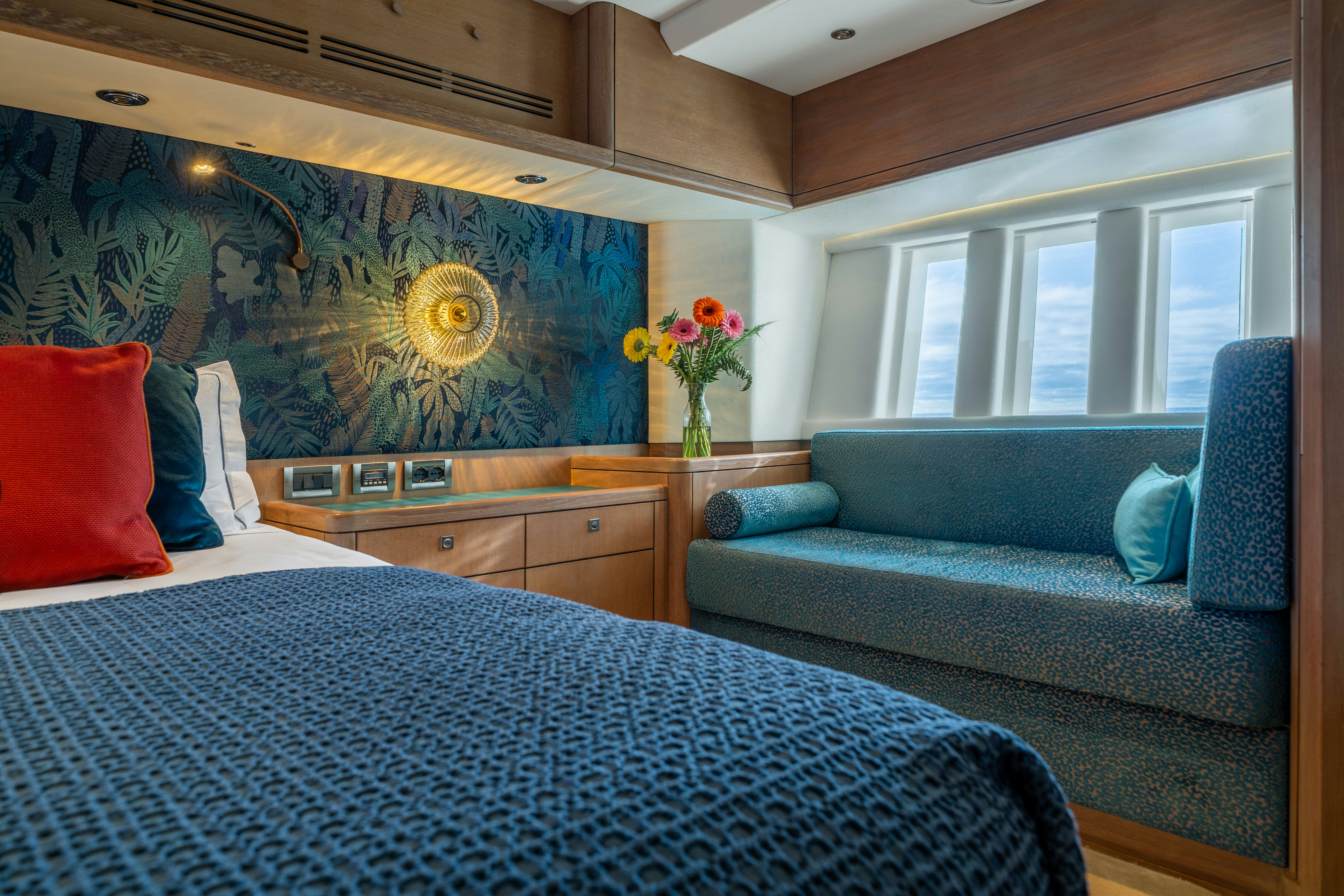 a bedroom with a blue couch and a painting on the wall aboard KARIBU Yacht for Sale