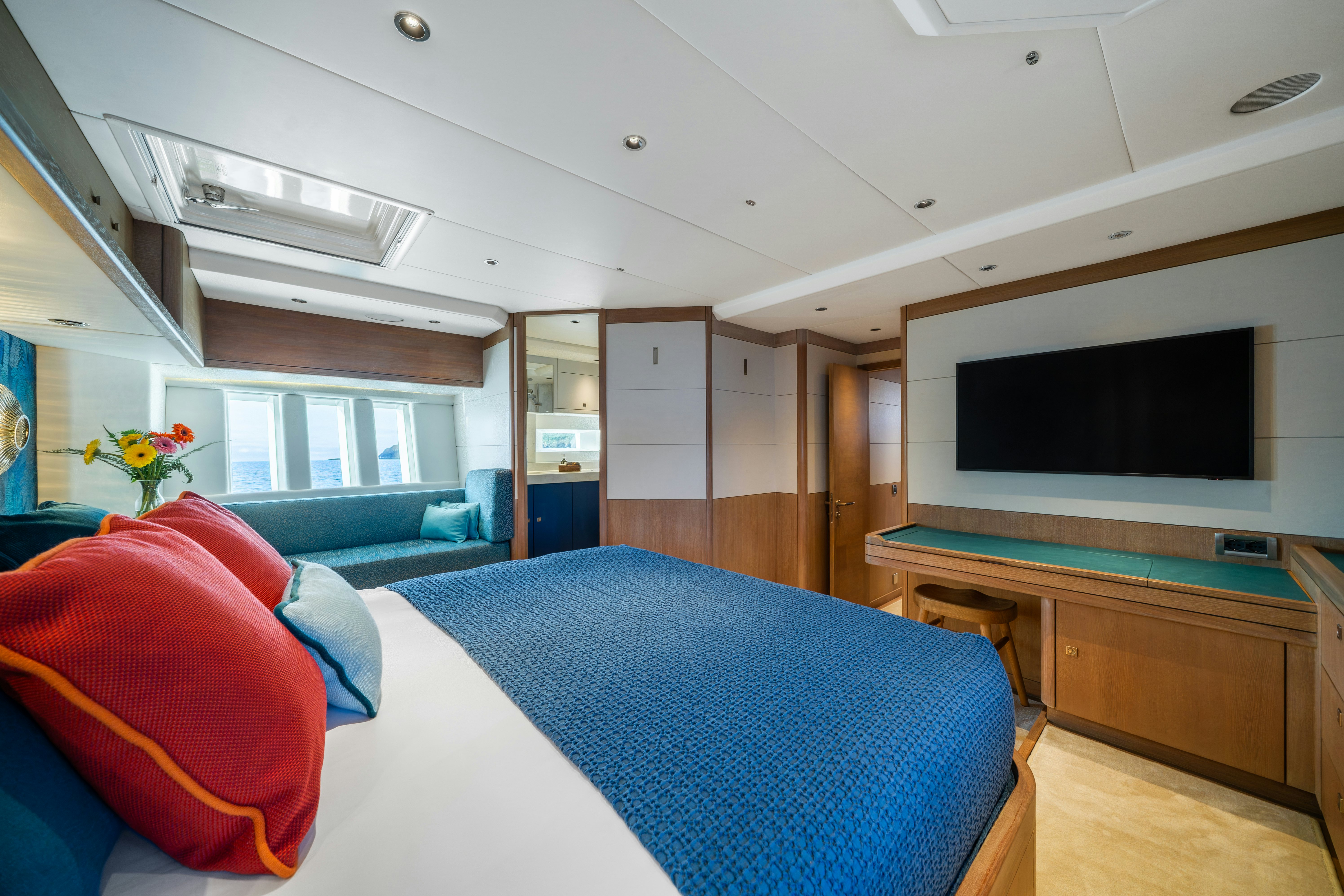 a bedroom with a blue bed and red pillows aboard KARIBU Yacht for Sale