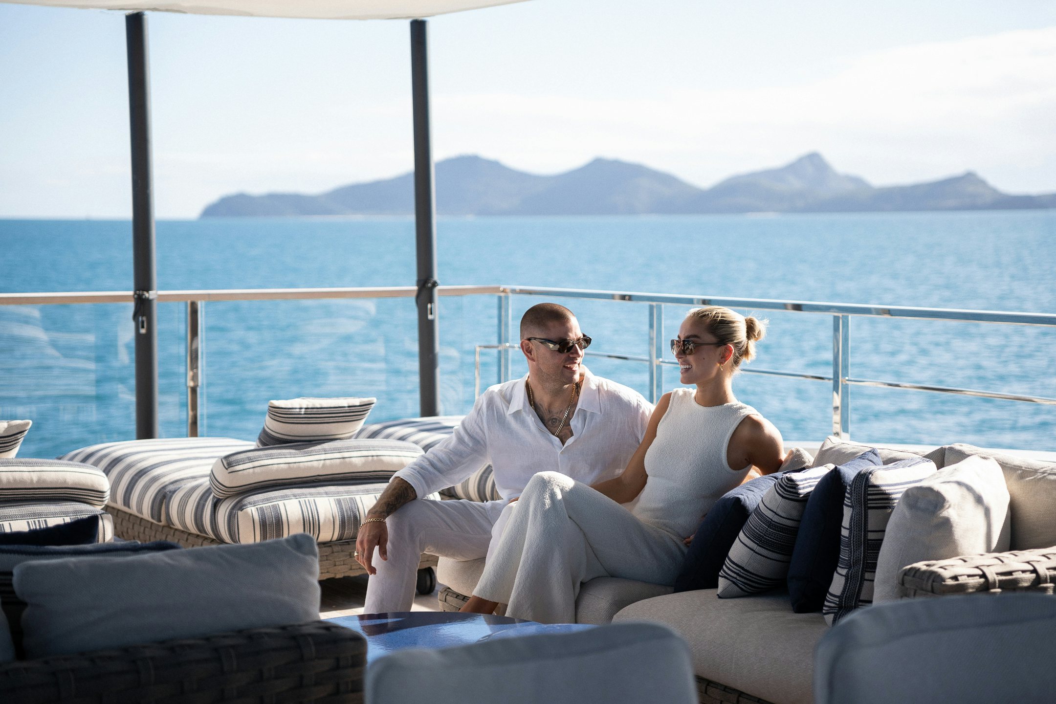 a man and woman sitting on a couch overlooking the ocean aboard AIX Yacht for Charter