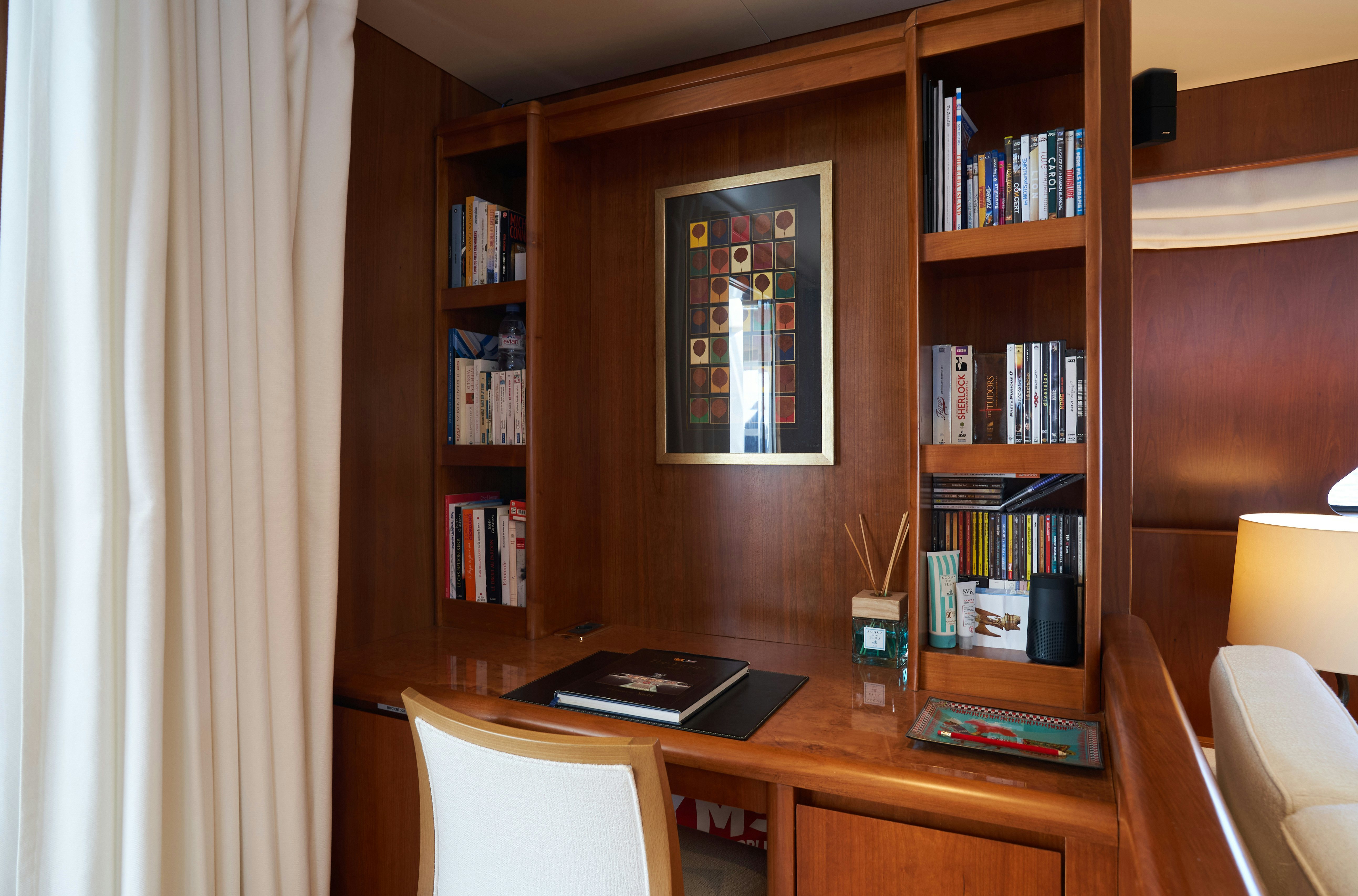 a desk with a laptop and books on it aboard L'INSTANT IV Yacht for Sale