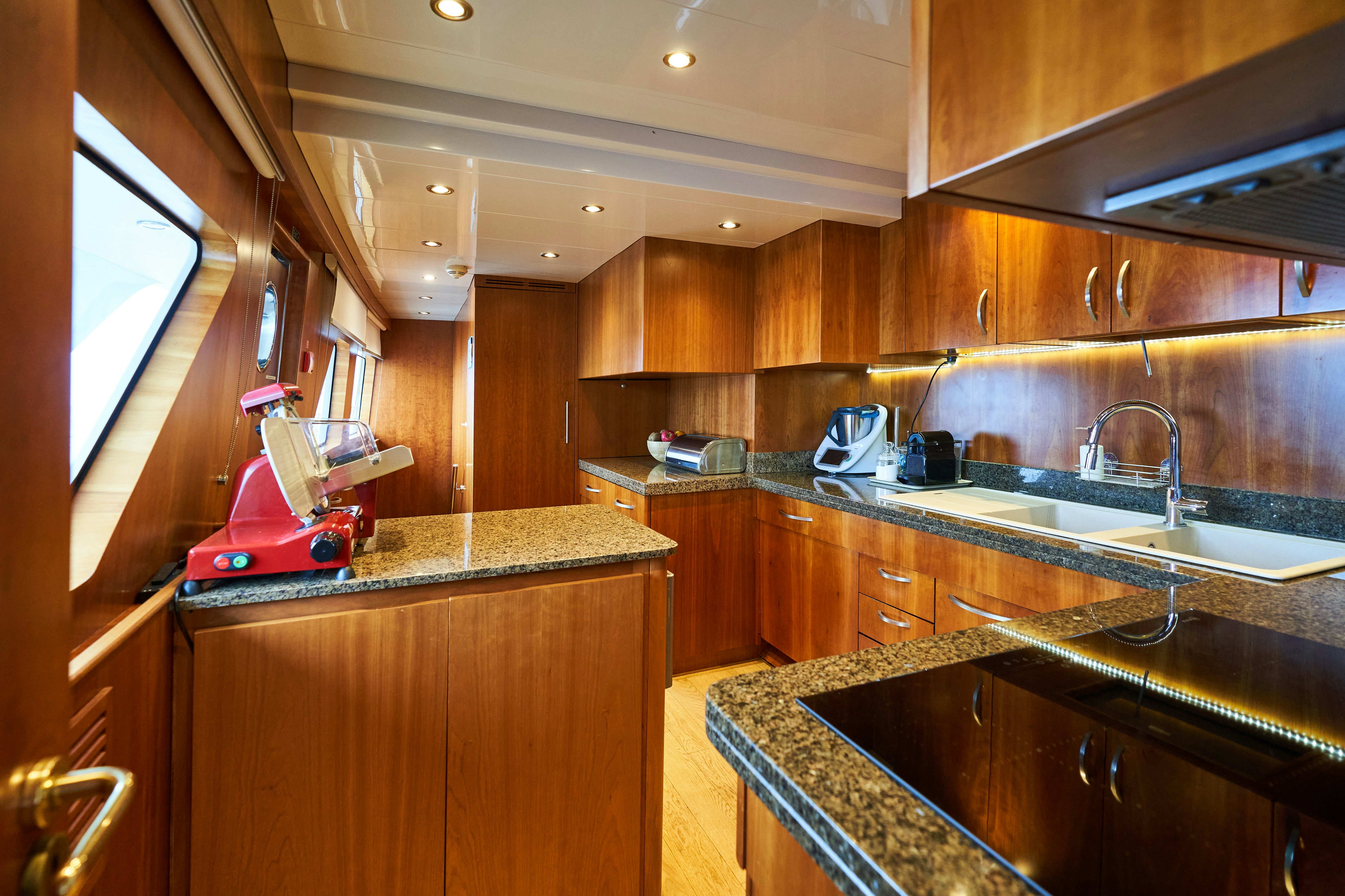a kitchen with wooden cabinets aboard L'INSTANT IV Yacht for Sale