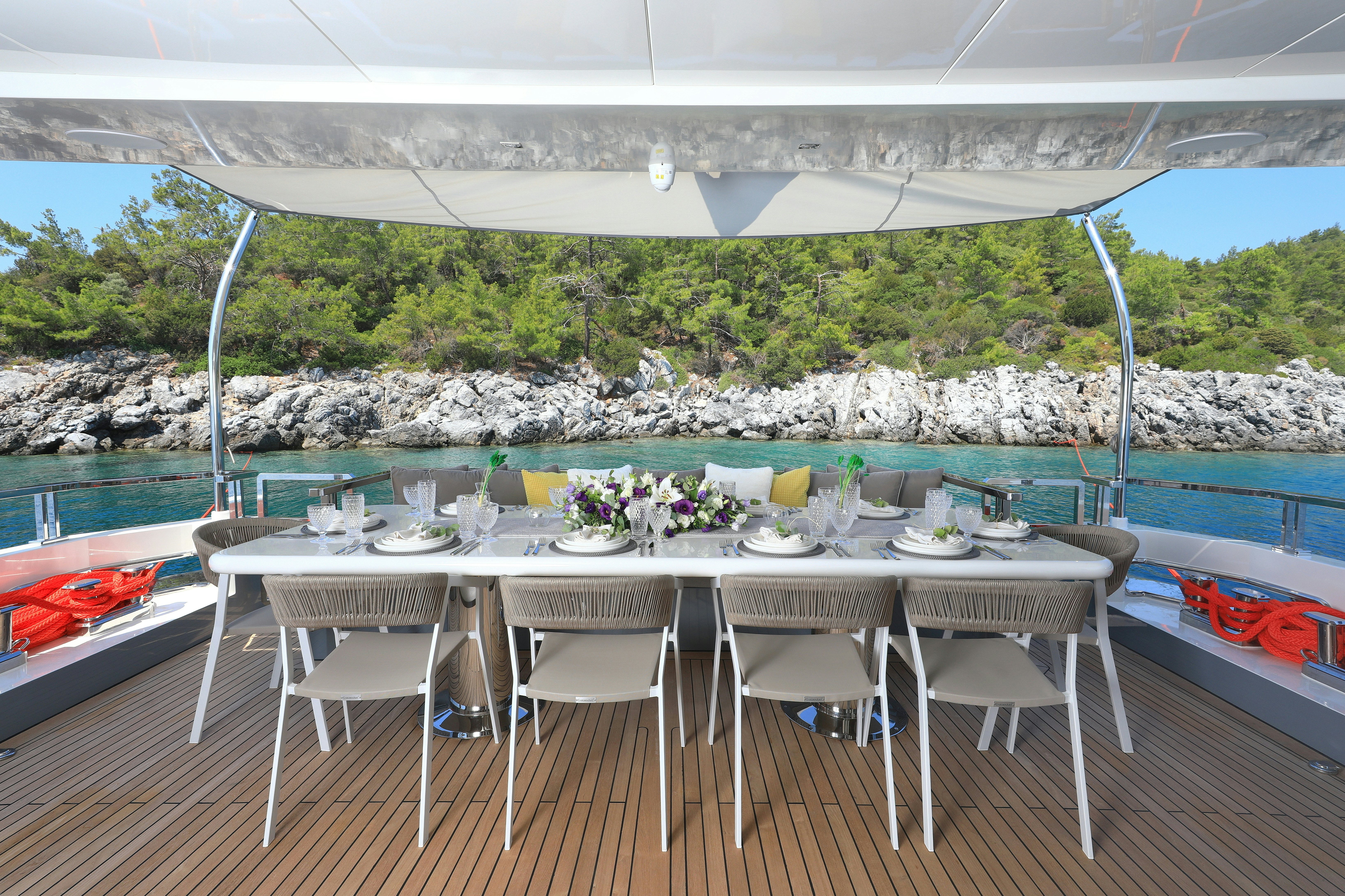 a table set for a meal on a deck overlooking a body of water aboard AEGEAN EXPLORER 26M HULL #3 Yacht for Sale