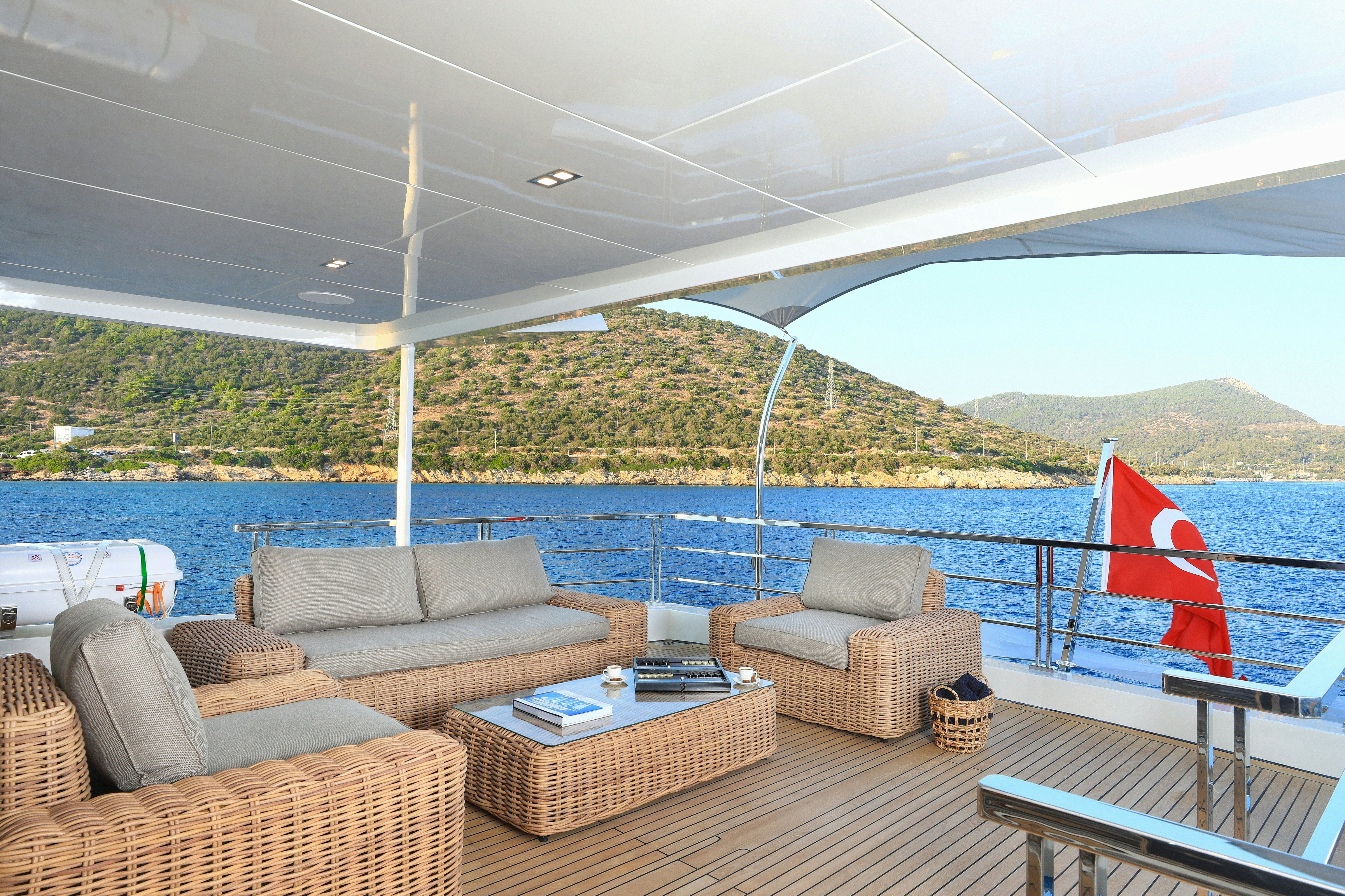 a deck with a couch and a flag on it aboard AEGEAN EXPLORER 26M HULL #3 Yacht for Sale