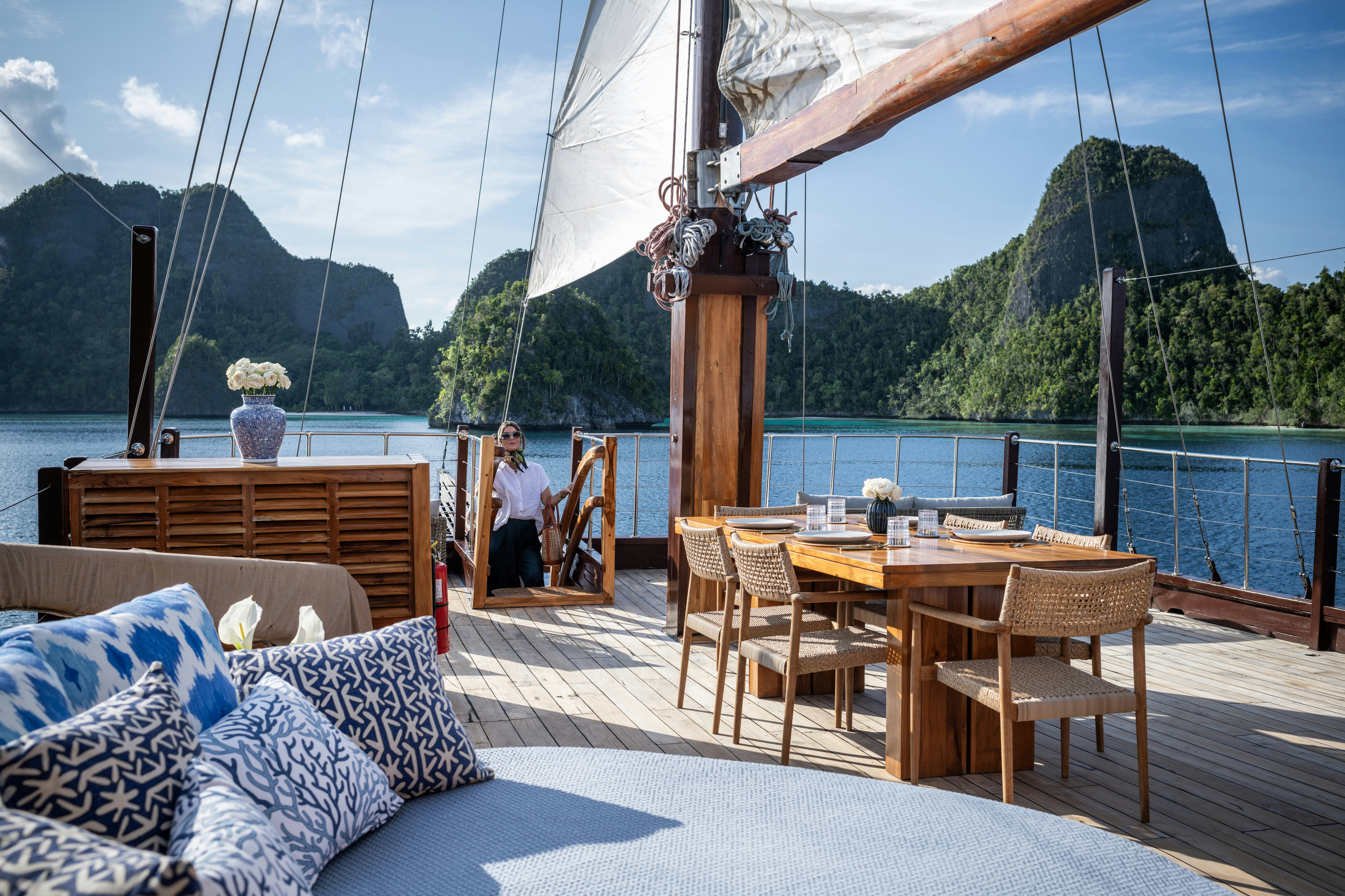 a person sitting at a table on a deck overlooking a large body of water aboard SEQUOIA Yacht for Charter