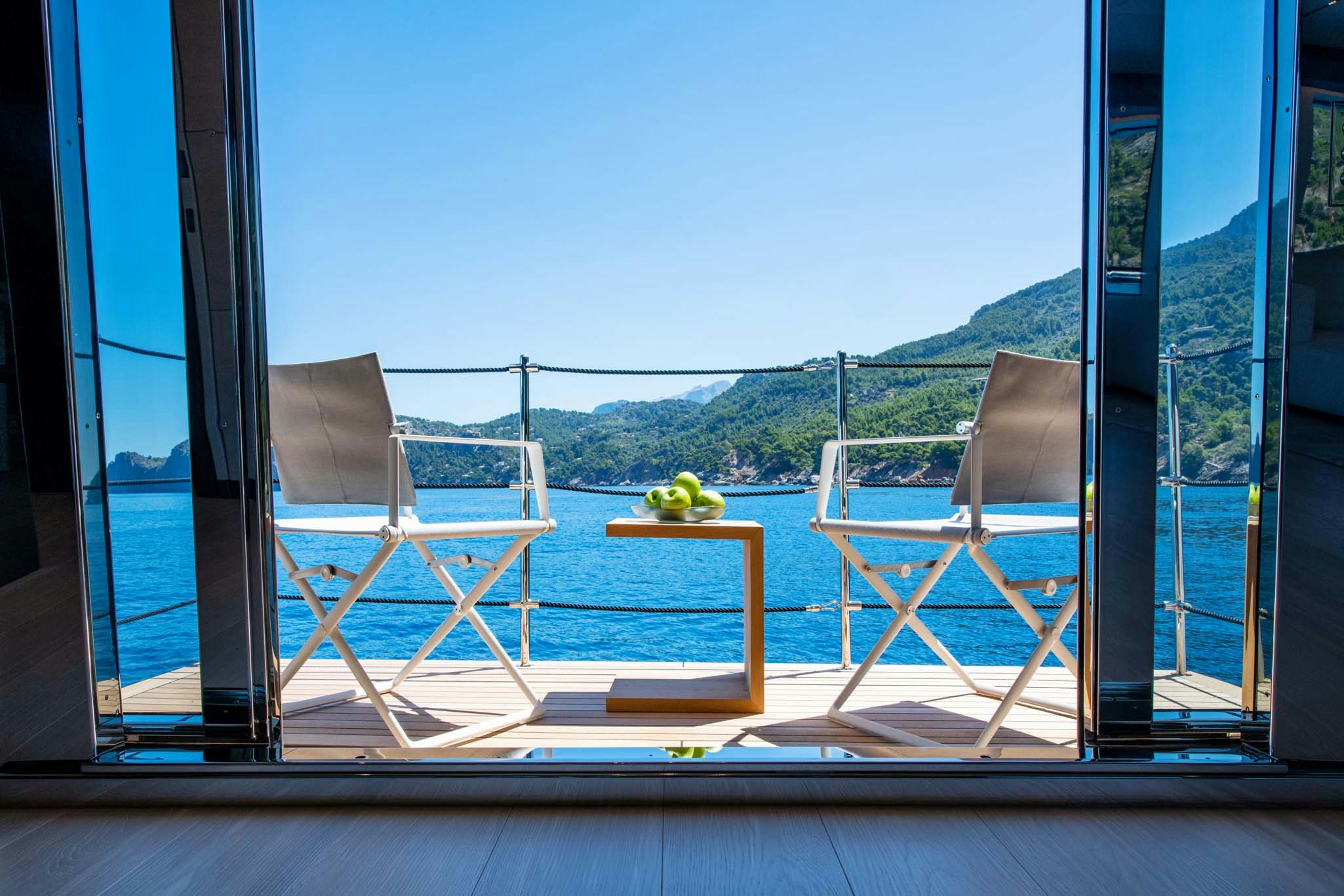 a glass table with a glass top and a chair on a balcony aboard PALOMA Yacht for Charter