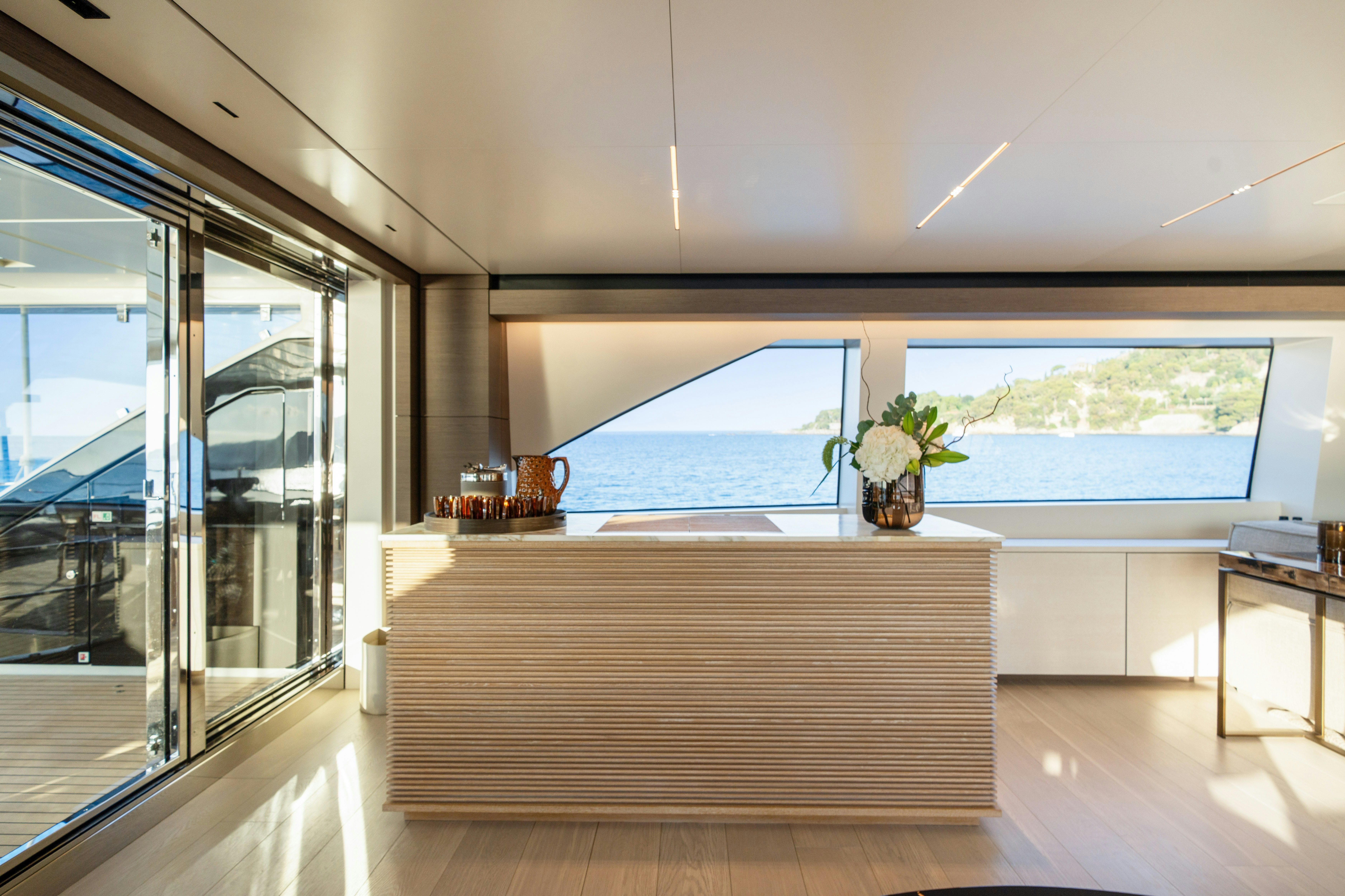 a room with a large window and a table with plants and a large body of water aboard PALOMA Yacht for Charter