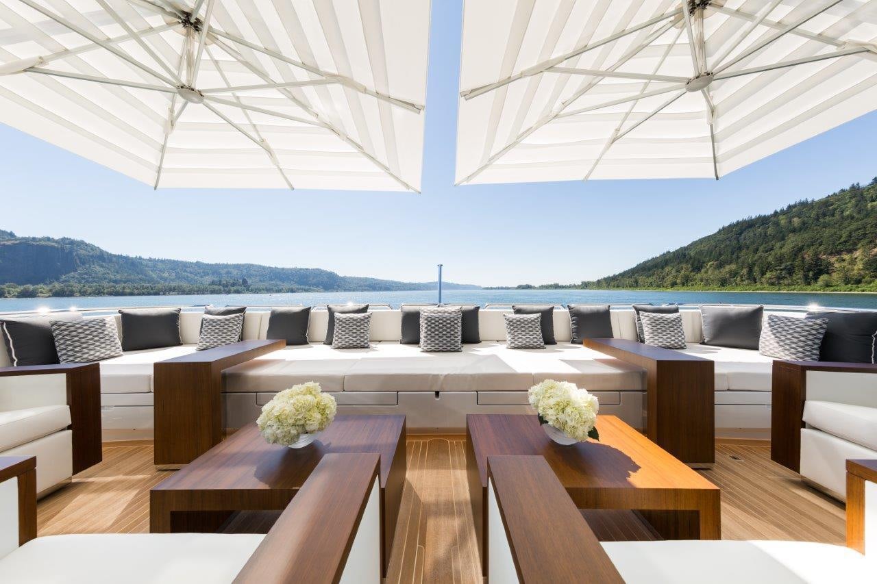 a large white tent with a table and chairs and a large body of water in the background aboard CHASSEUR Yacht for Charter
