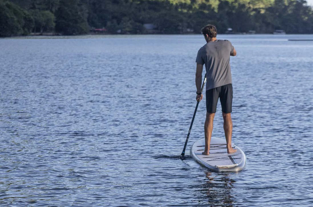 a man paddle boarding on a lake aboard AWANDRA Yacht for Charter