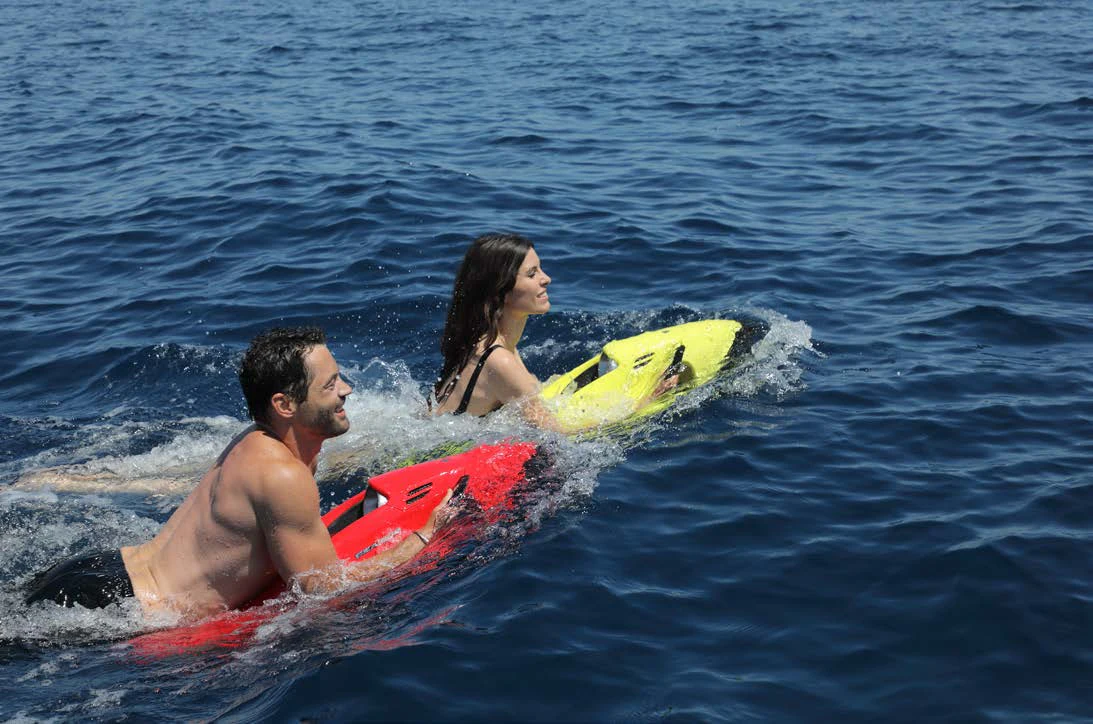 a man and woman sitting on surfboards in the water aboard AWANDRA Yacht for Charter