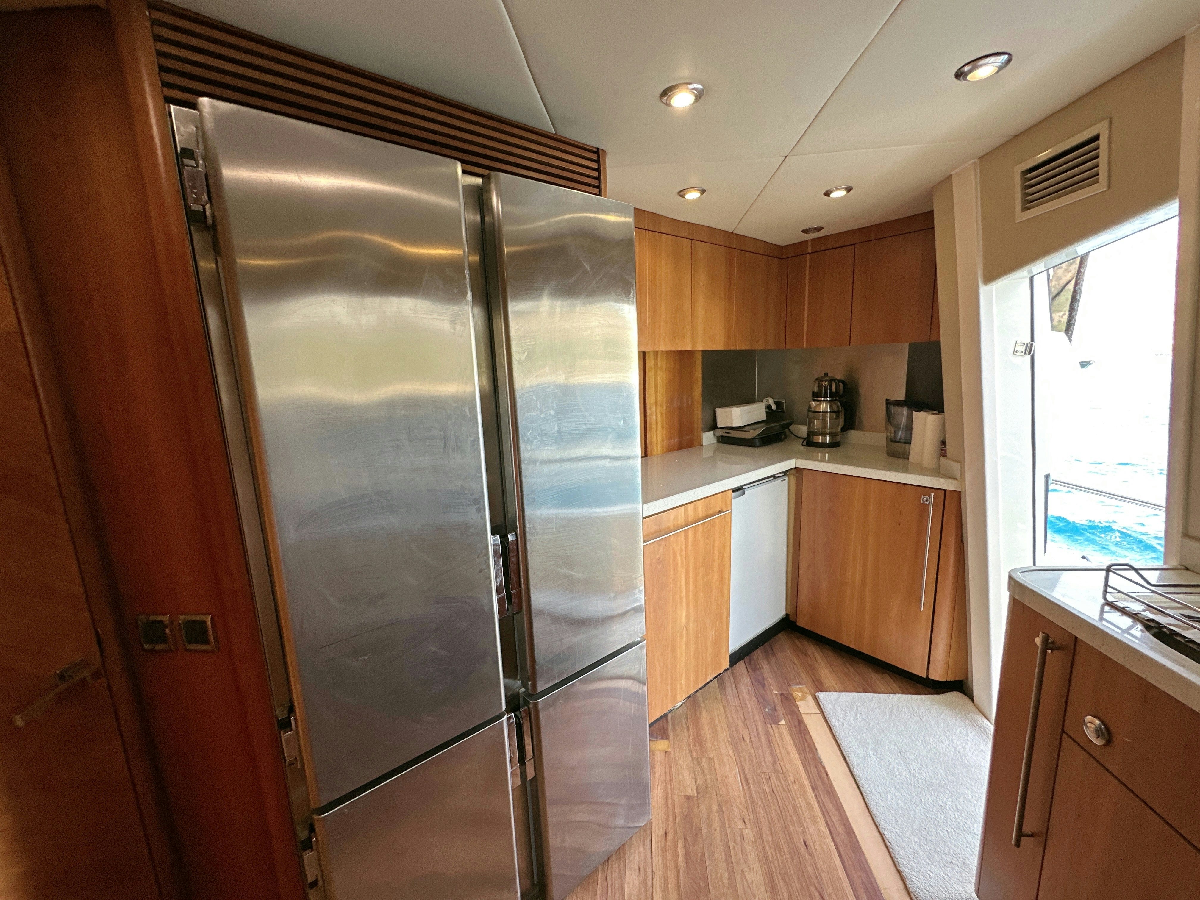 a large kitchen with a stainless steel refrigerator aboard SWORDFISH 68 Yacht for Sale