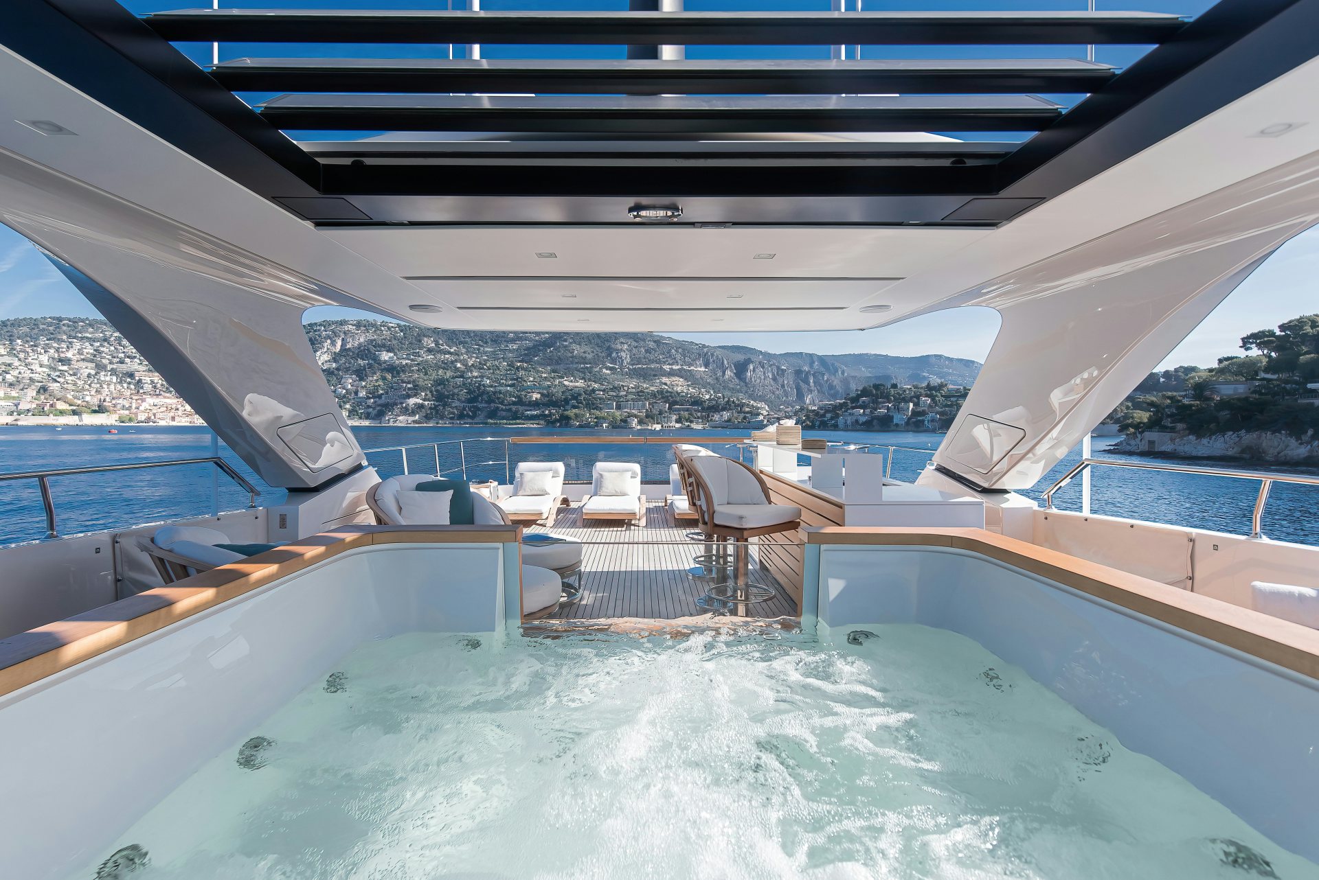 a swimming pool with chairs and a deck and mountains in the background aboard PREMURA Yacht for Charter