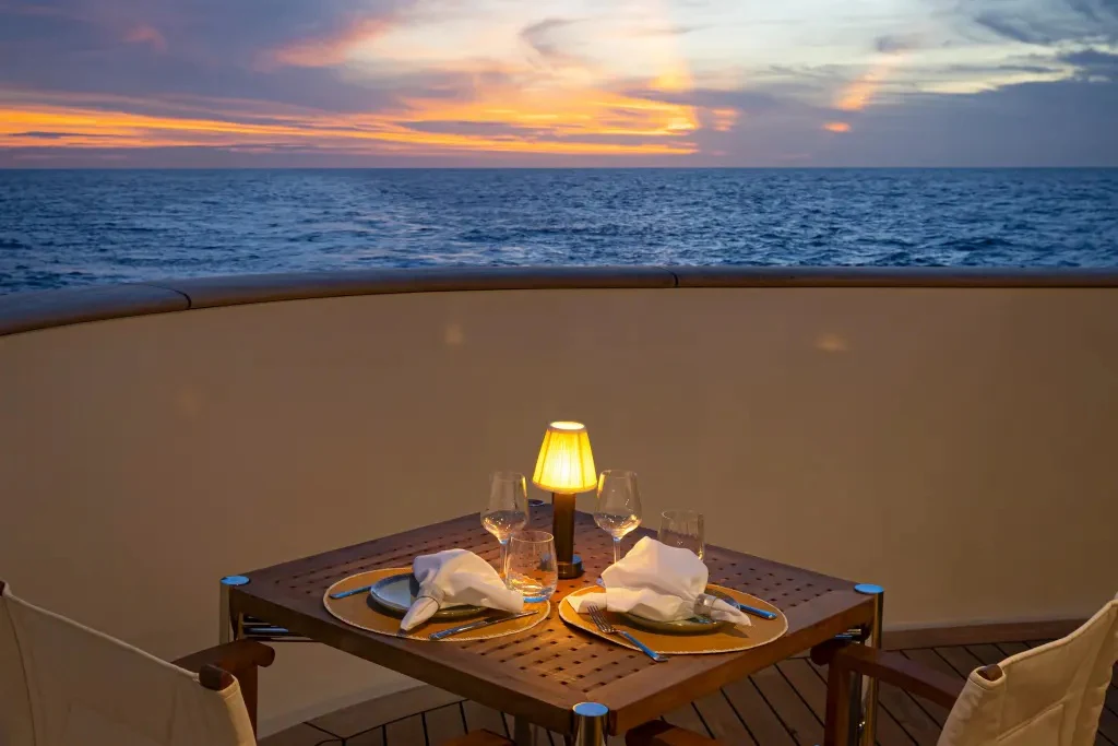 a table with glasses and a candle on it by the ocean aboard LEGEND Yacht for Charter