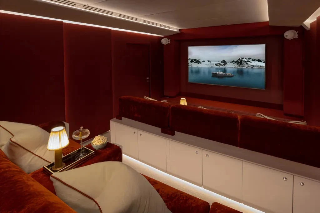 a room with a red couch and a television on the wall aboard LEGEND Yacht for Charter