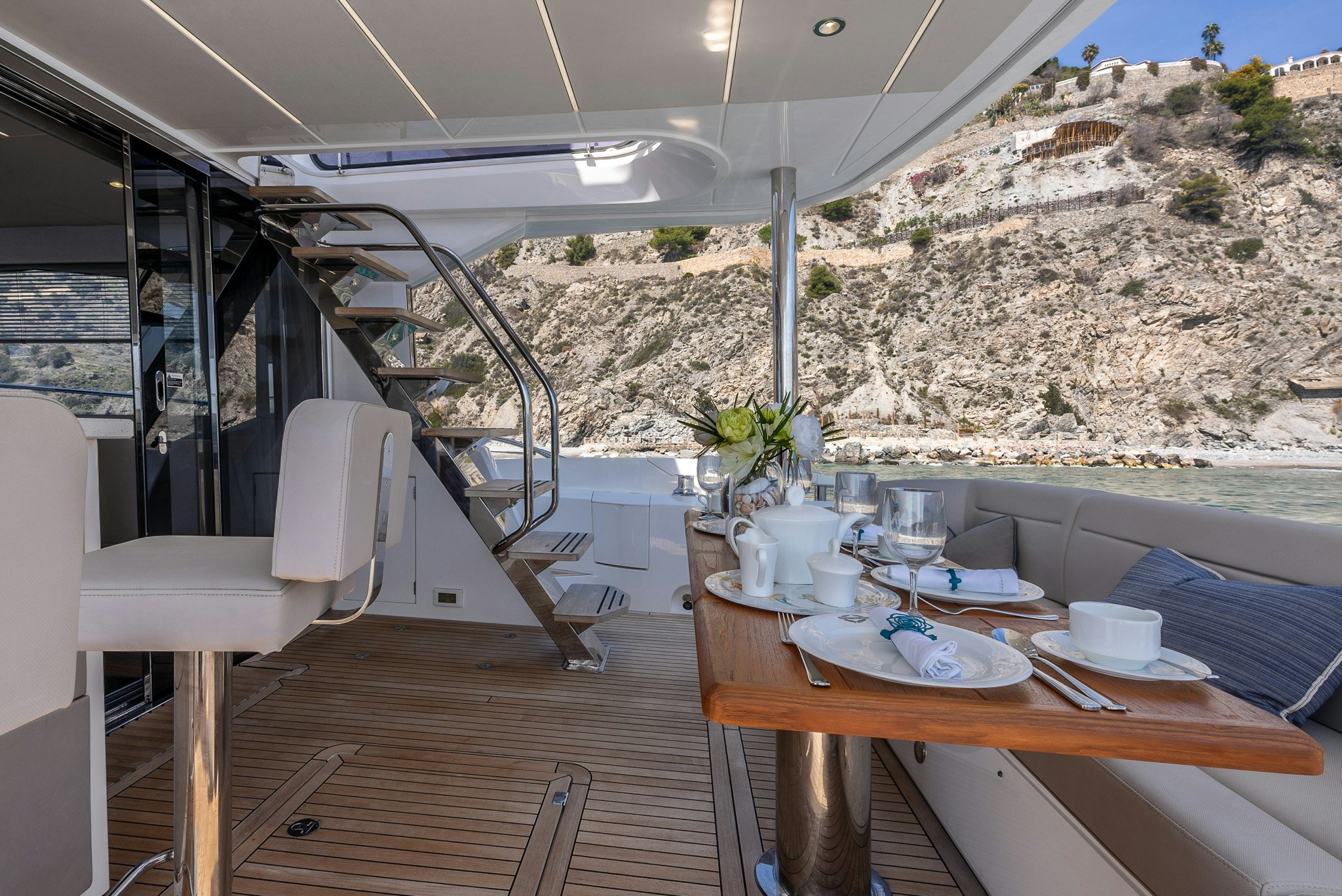a table with chairs and a view of a mountain range aboard ISLA DE FLORA Yacht for Sale