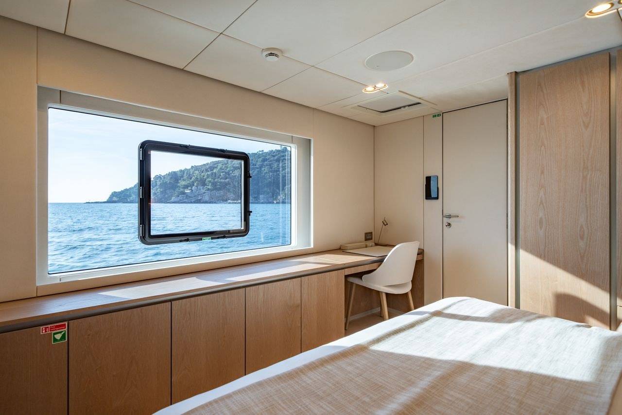 a room with a bed and a large window aboard PETITE BELLE Yacht for Sale