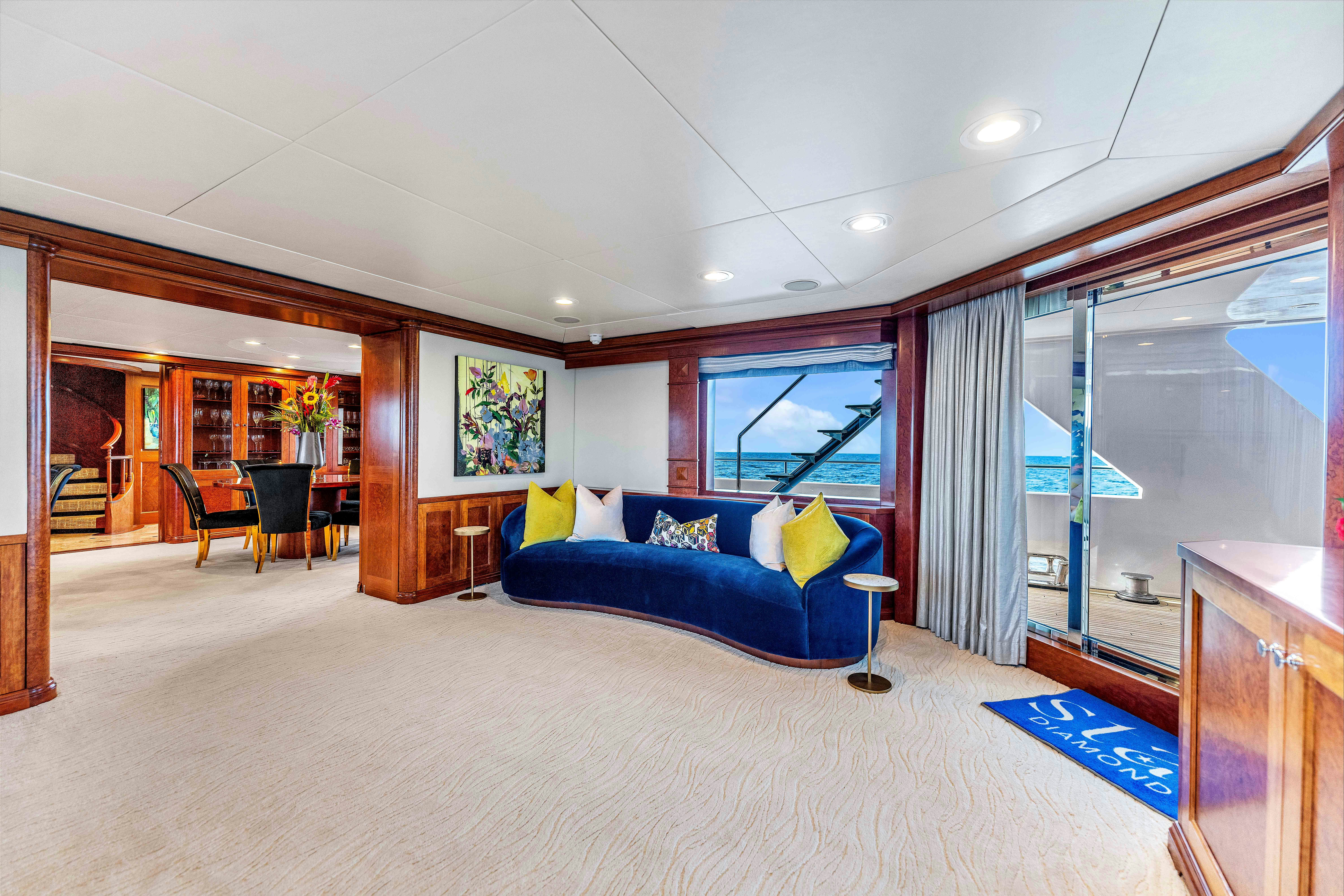 a large living room with a blue couch and a large window aboard STAR DIAMOND Yacht for Sale