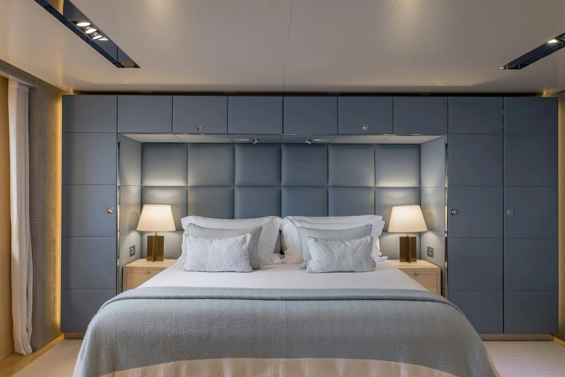a bed with a blue wall aboard LOON Yacht for Charter