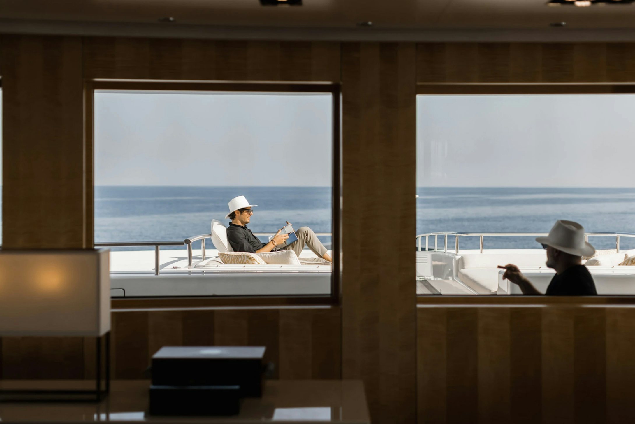 a person sitting at a desk in a room with a large window aboard LOON Yacht for Charter